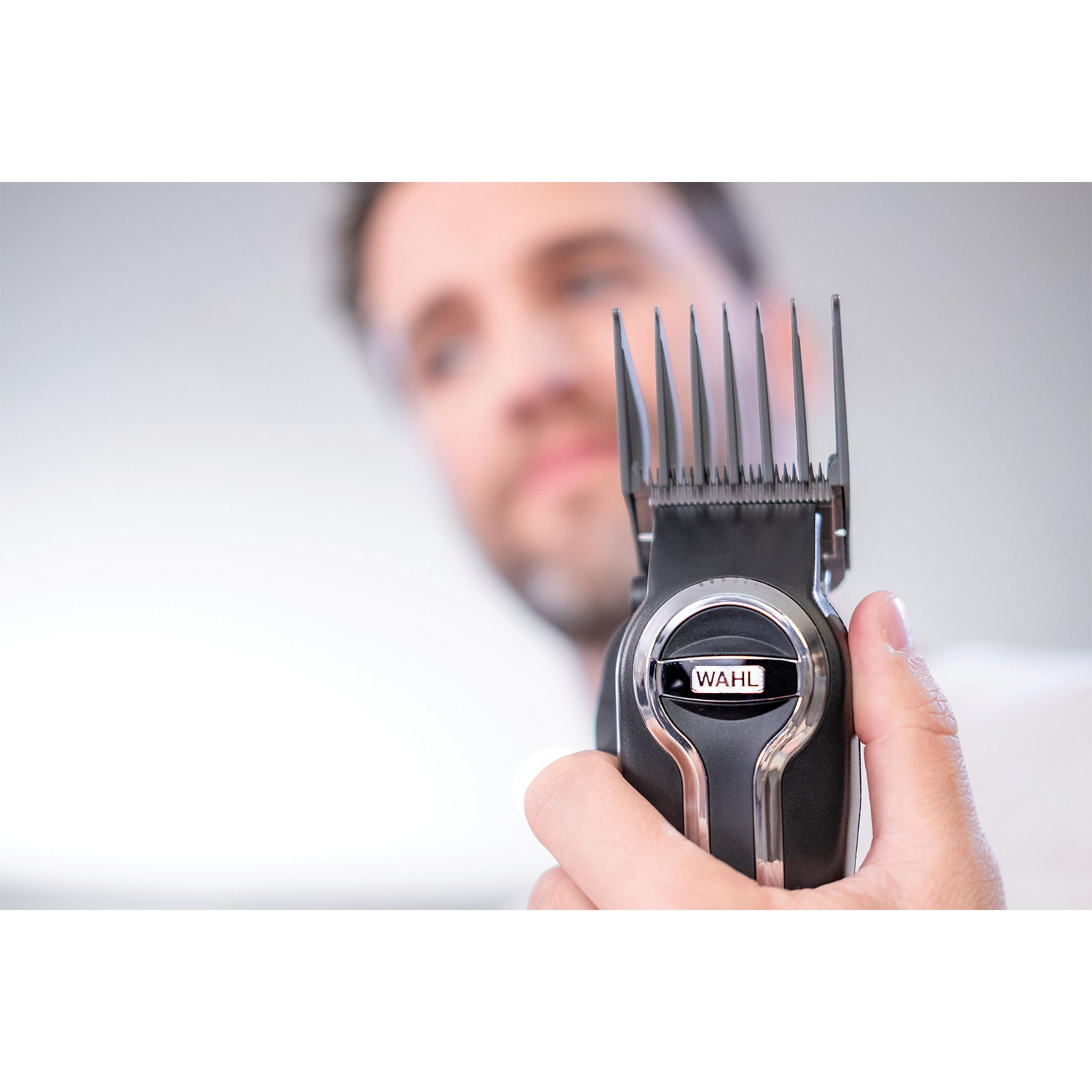 Mężczyzna trzyma w dłoni czarną maszynkę do strzyżenia Wahl z nasadką.