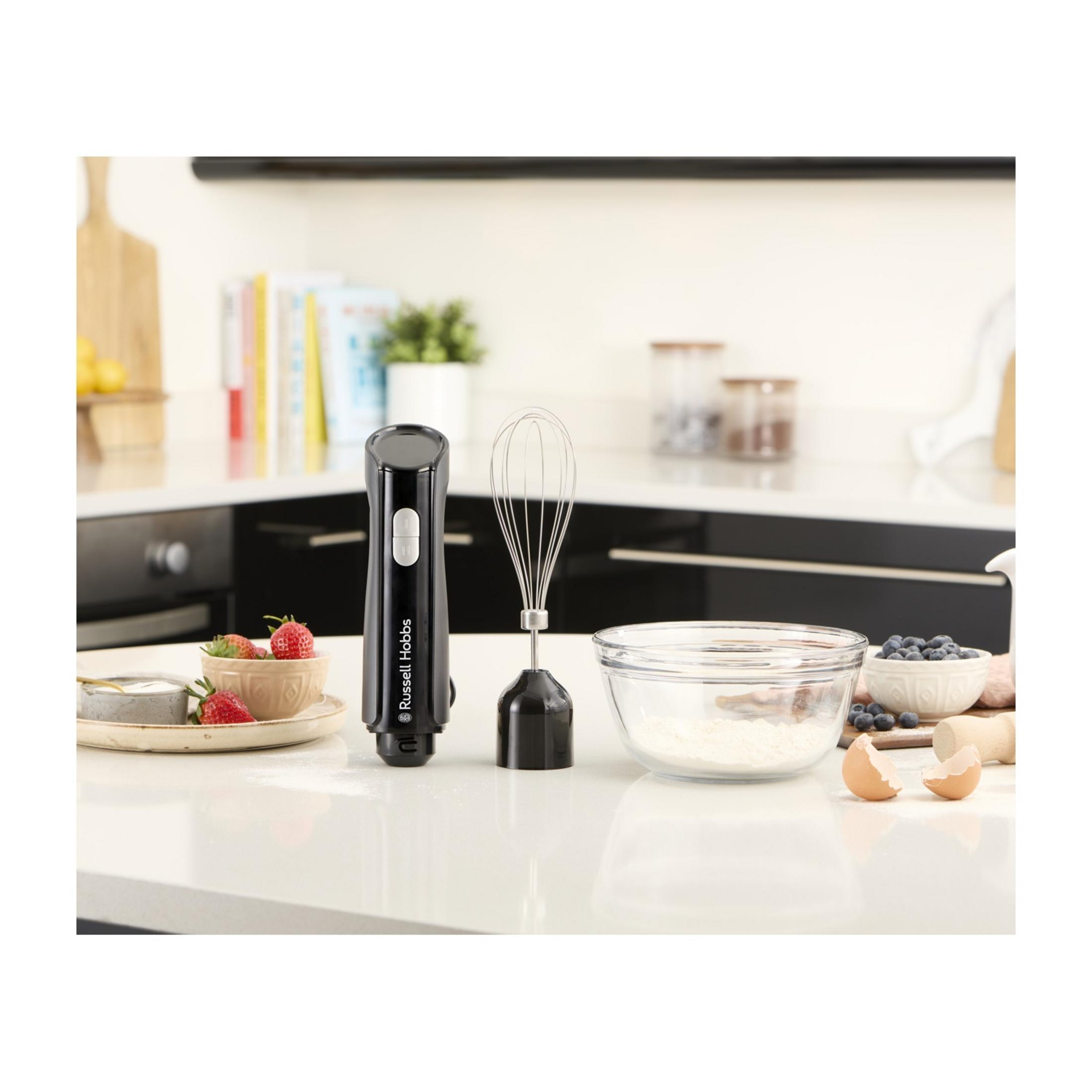 Czarny blender ręczny z trzepaczką, truskawkami, borówkami, mąką i skorupkami jaj.