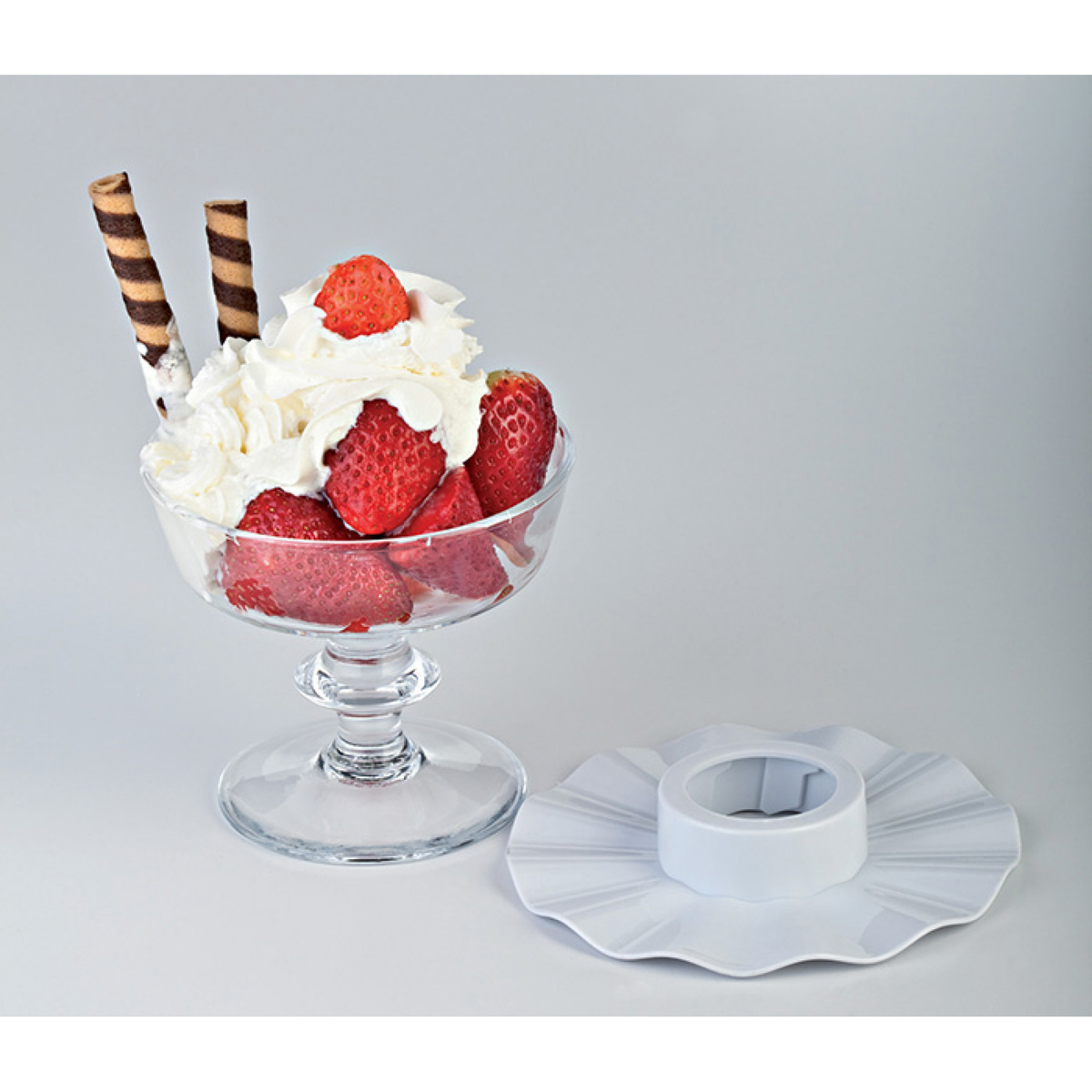 Un vaso de fresas con nata montada y barquillos.