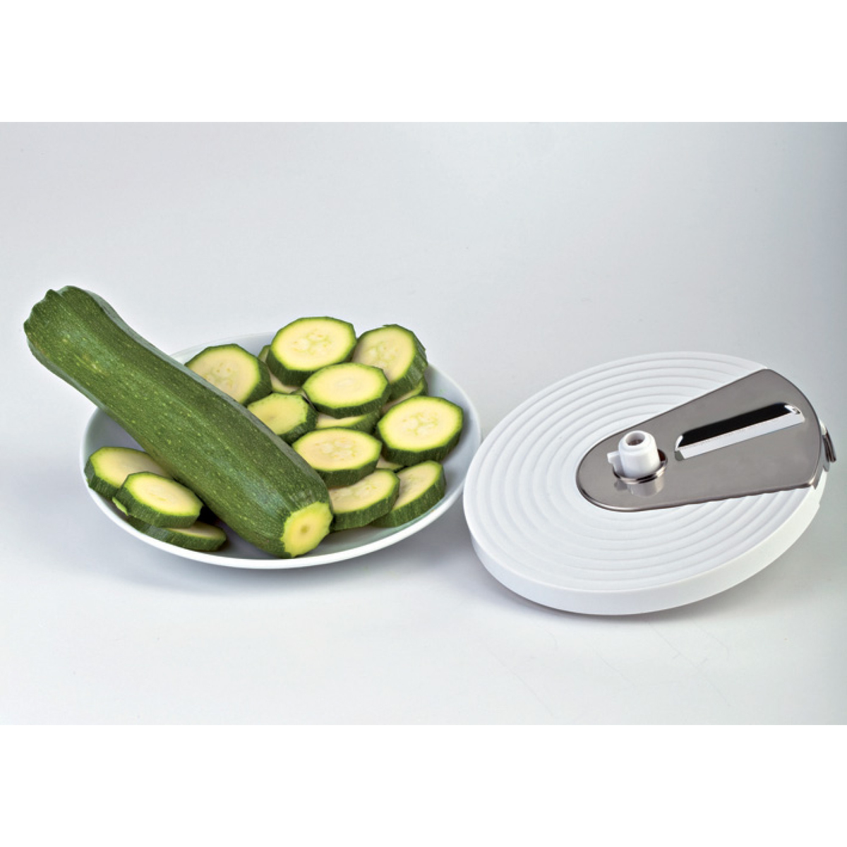 Una calabacina yace junto a un bol de rodajas de calabacín y un accesorio espiralizador.