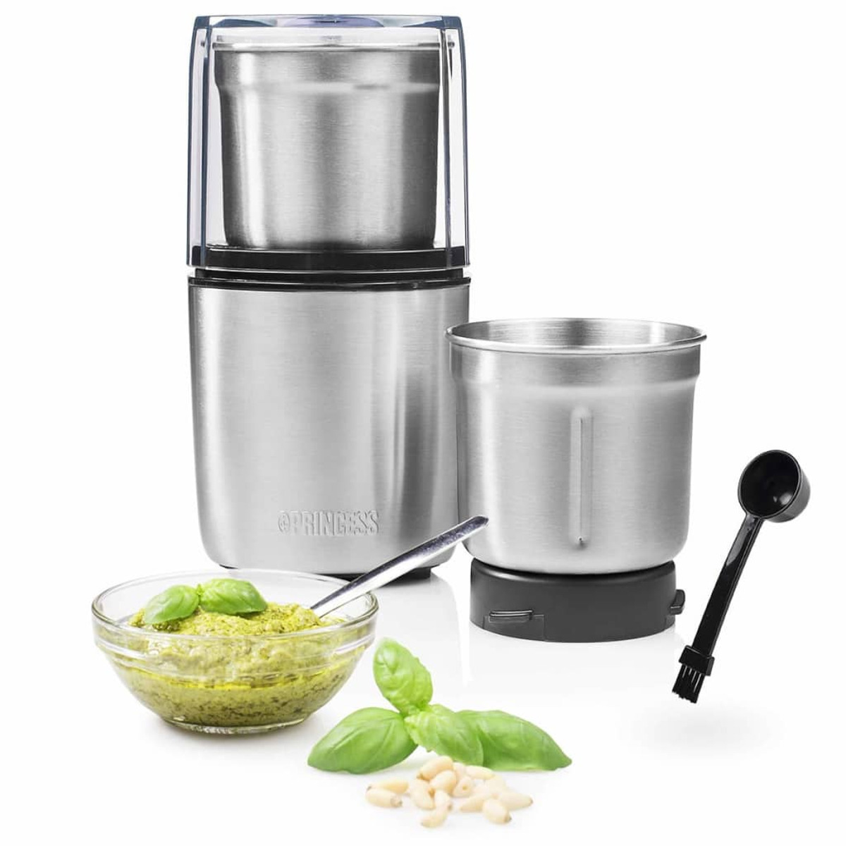 Stainless steel grinder with accessories, pesto, pine nuts, and basil on white.