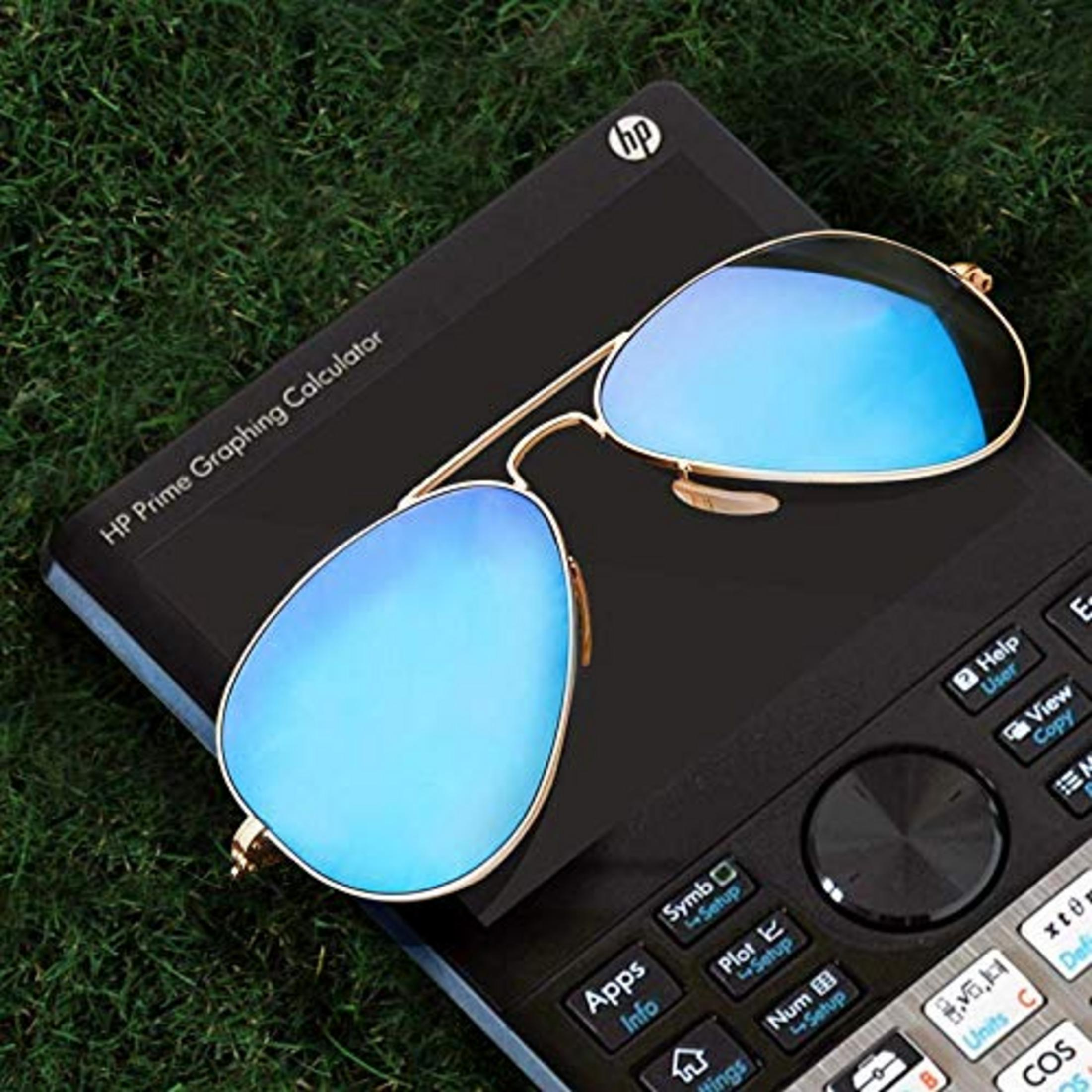 Lunettes de soleil aviateur à verres miroirs bleus reposent sur une calculatrice graphique HP noire.