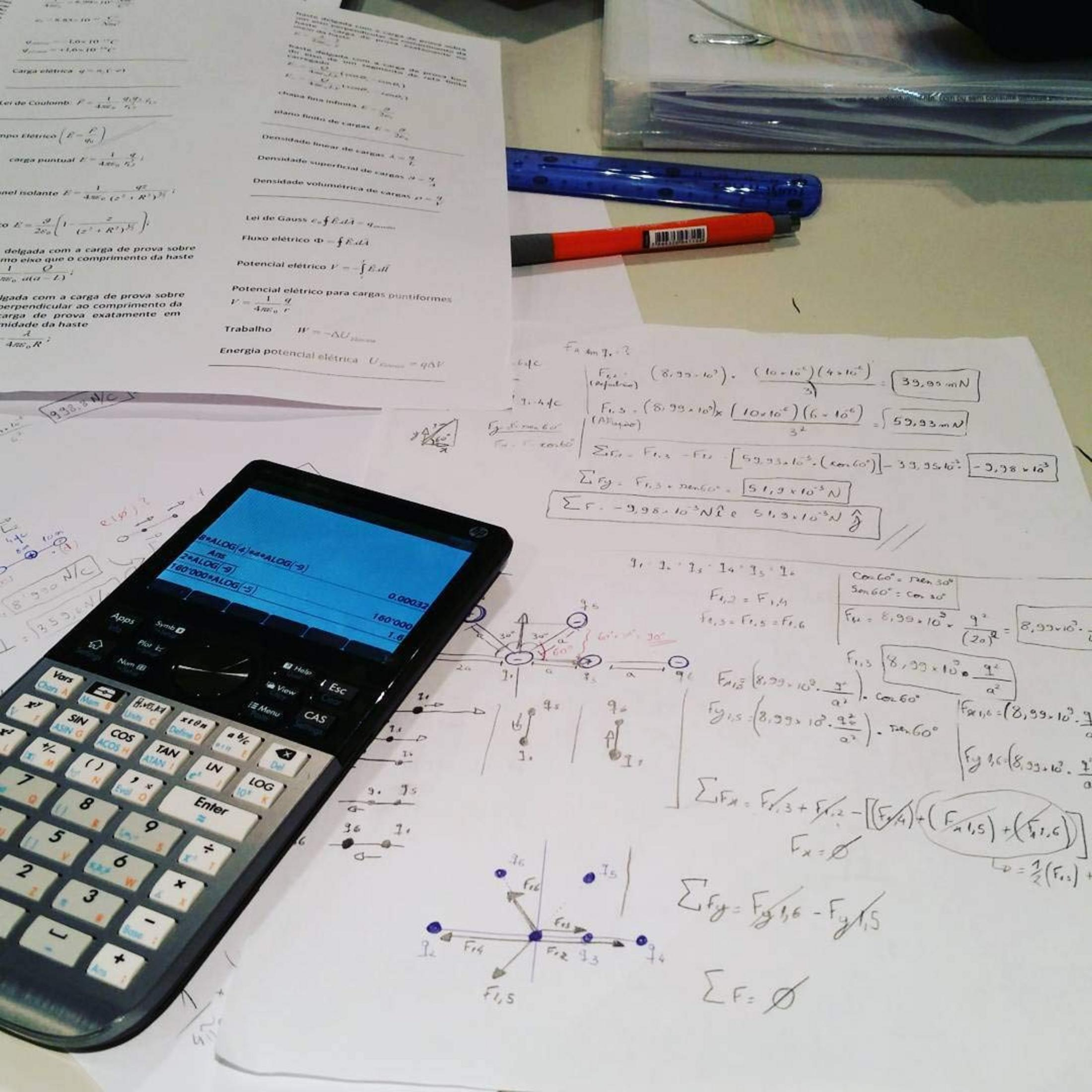 Un bureau avec des notes de physique, une calculatrice et des stylos.