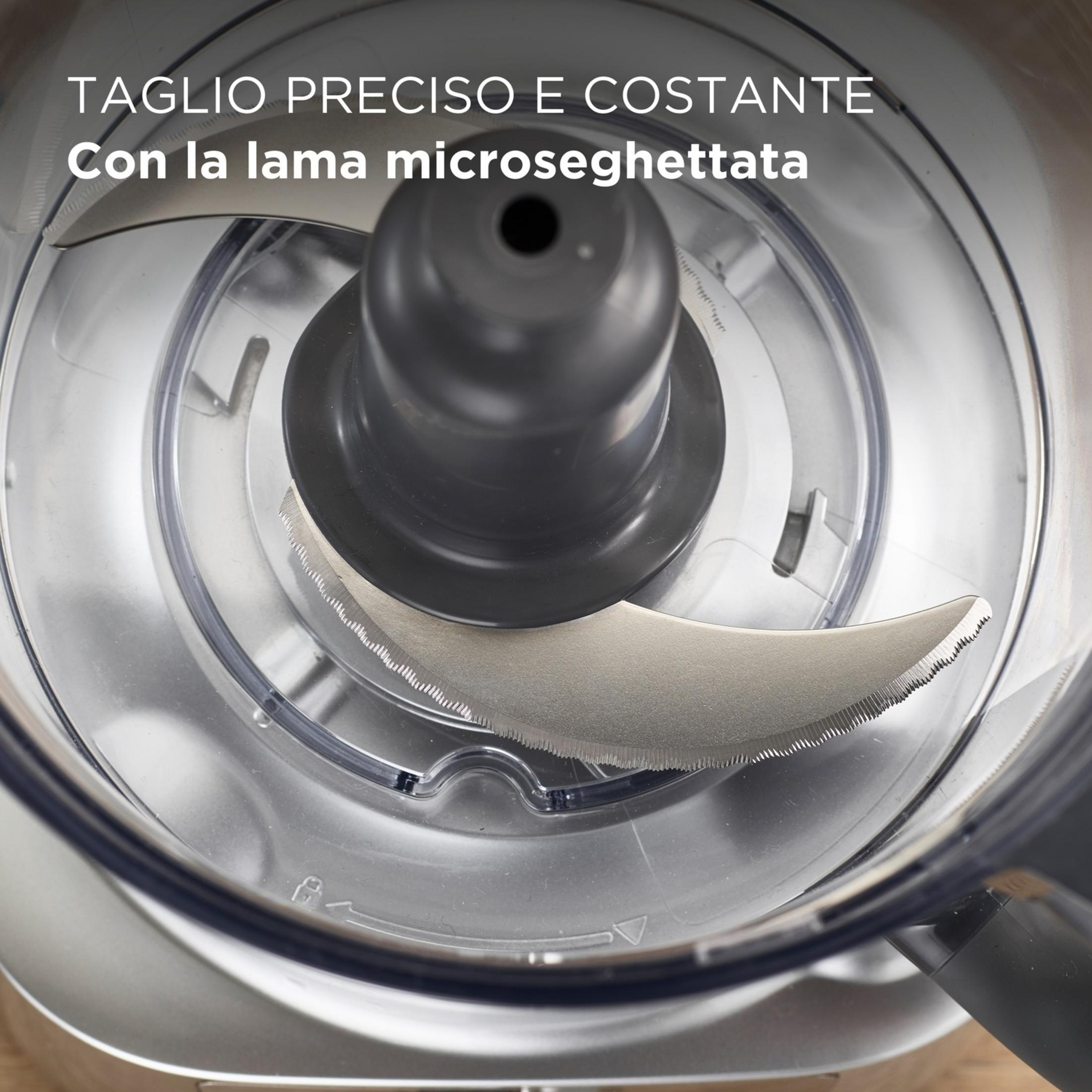 Primer plano de un procesador de alimentos con cuchilla dentada y recipiente transparente.