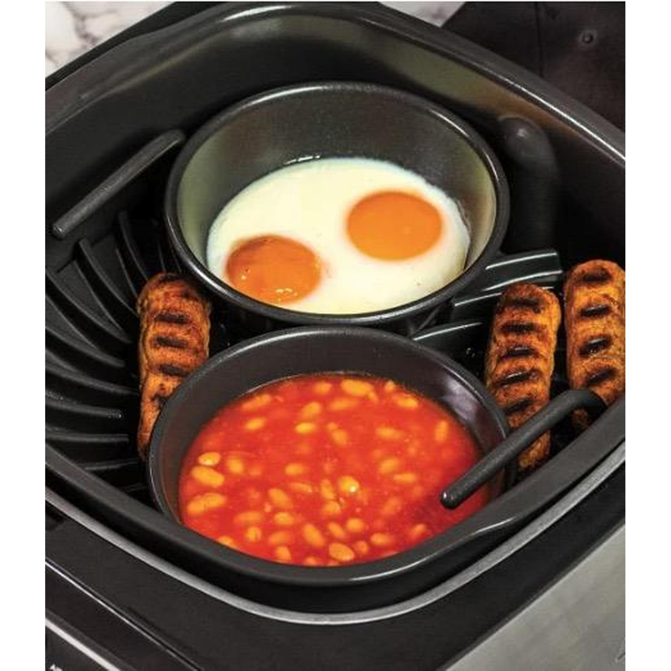 Frühstück mit zwei Spiegeleiern, gebackenen Bohnen und drei Würstchen in einem schwarzen Gerät.
