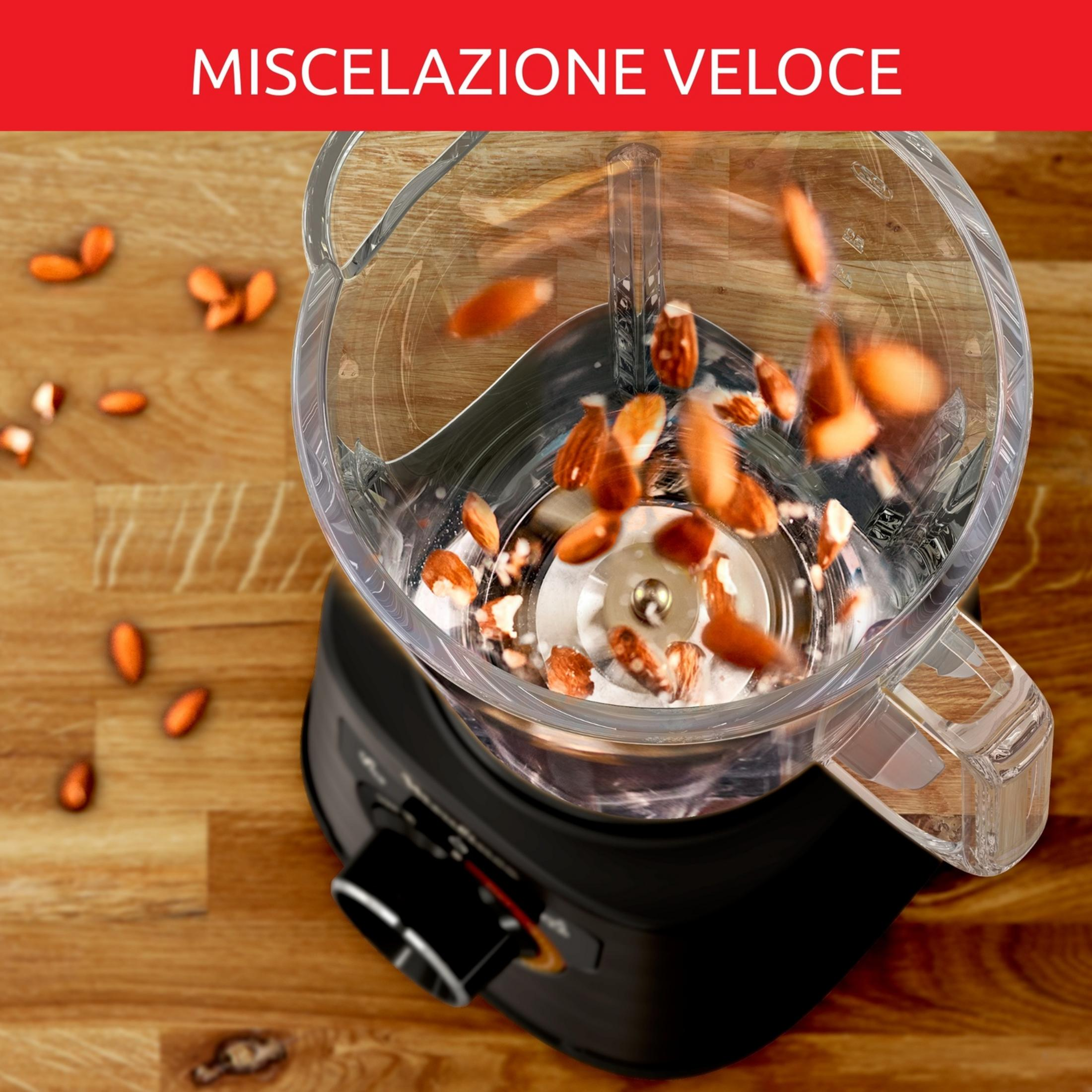 Mandorle volano in un frullatore su un tavolo di legno.