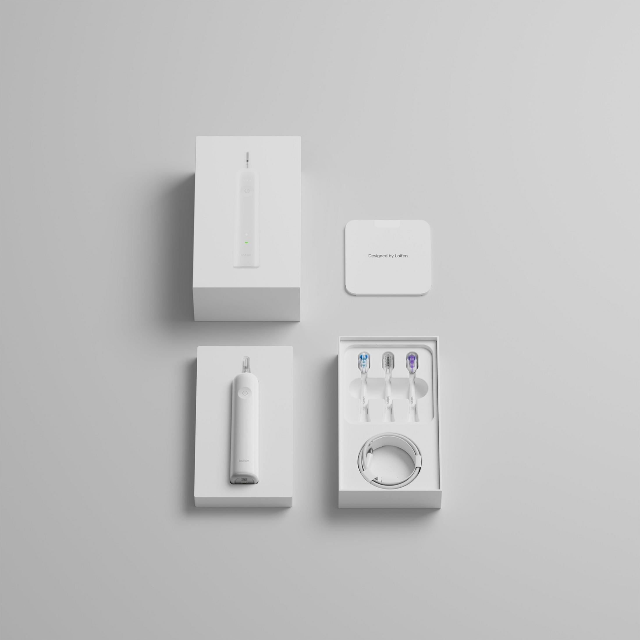 Biała szczoteczka elektryczna z trzema końcówkami i kablem ładującym.