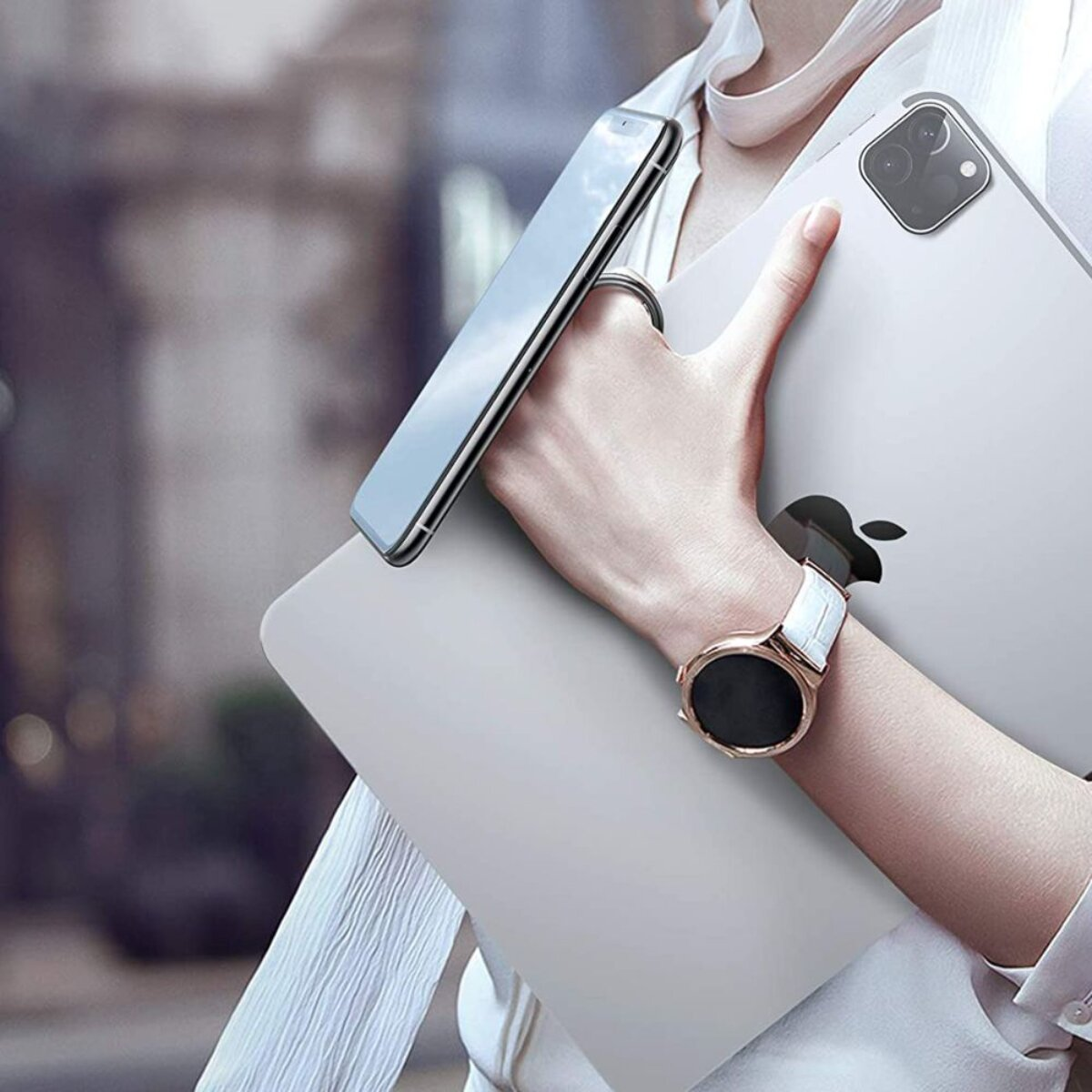 Person hält ein silbernes Tablet mit Apple-Logo und ein Smartphone. Armbanduhr.
