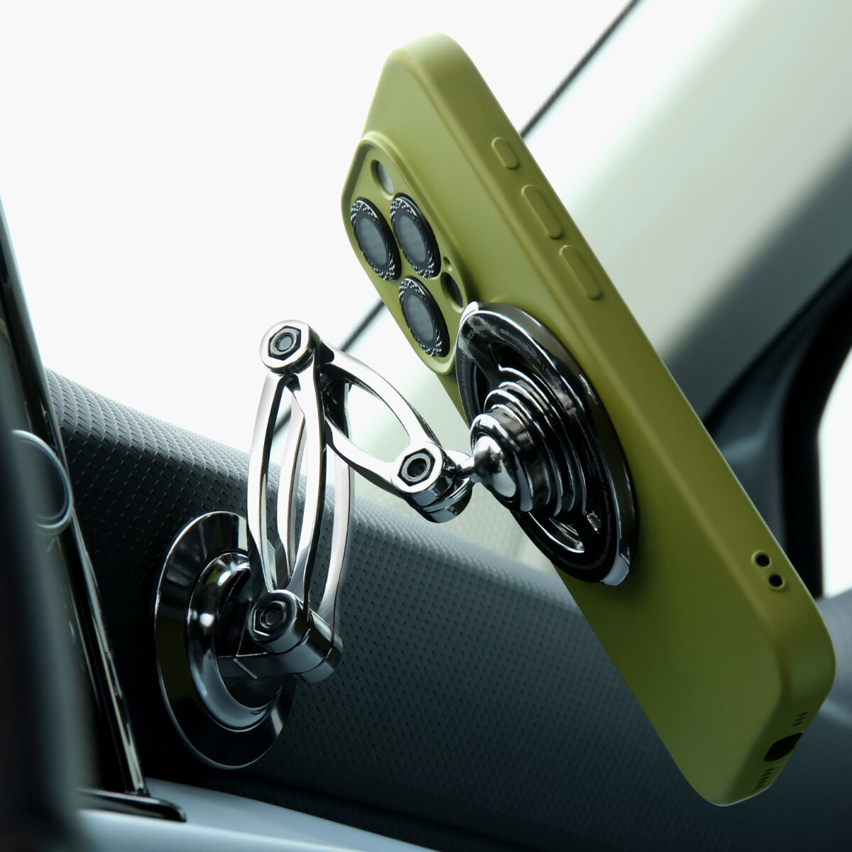 Ein olivgrünes Handy an einem glänzenden Metallhalter in einem Auto.