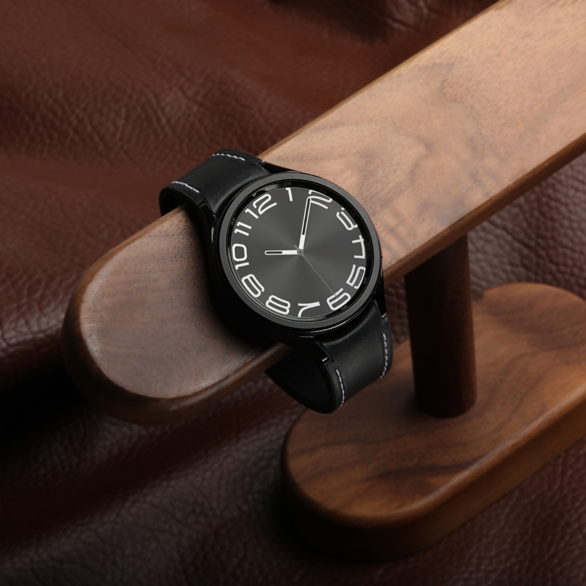 Orologio da polso nero con numeri bianchi su supporto in legno e pelle.