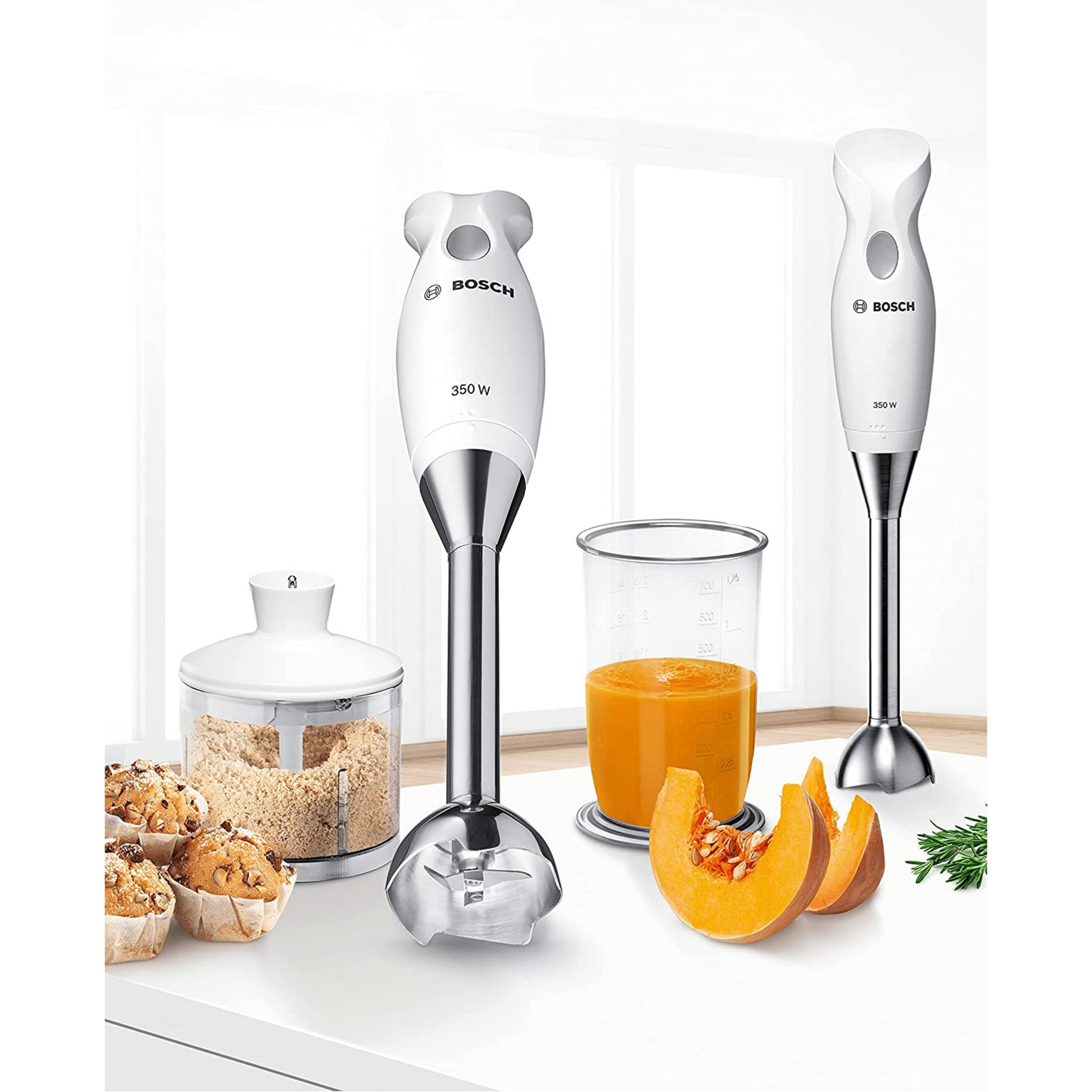 Een Bosch staafmixer met accessoires, muffins, pompoen en een beker sap.