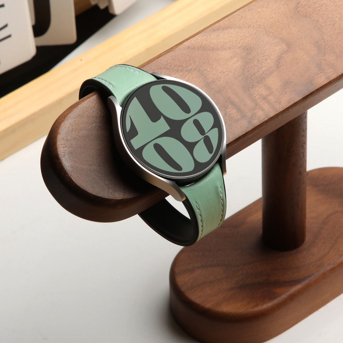 Eine grüne Smartwatch mit silbernem Gehäuse auf einem Holzständer.