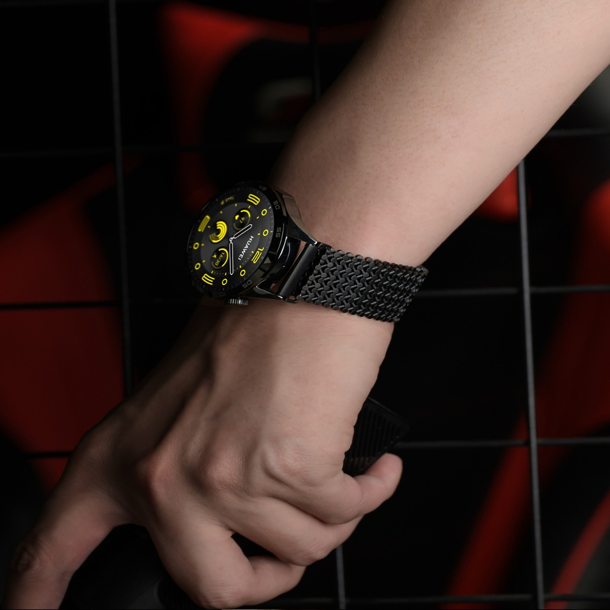 Eine Hand mit einer schwarzen Smartwatch mit gelben Akzenten auf dem Zifferblatt.