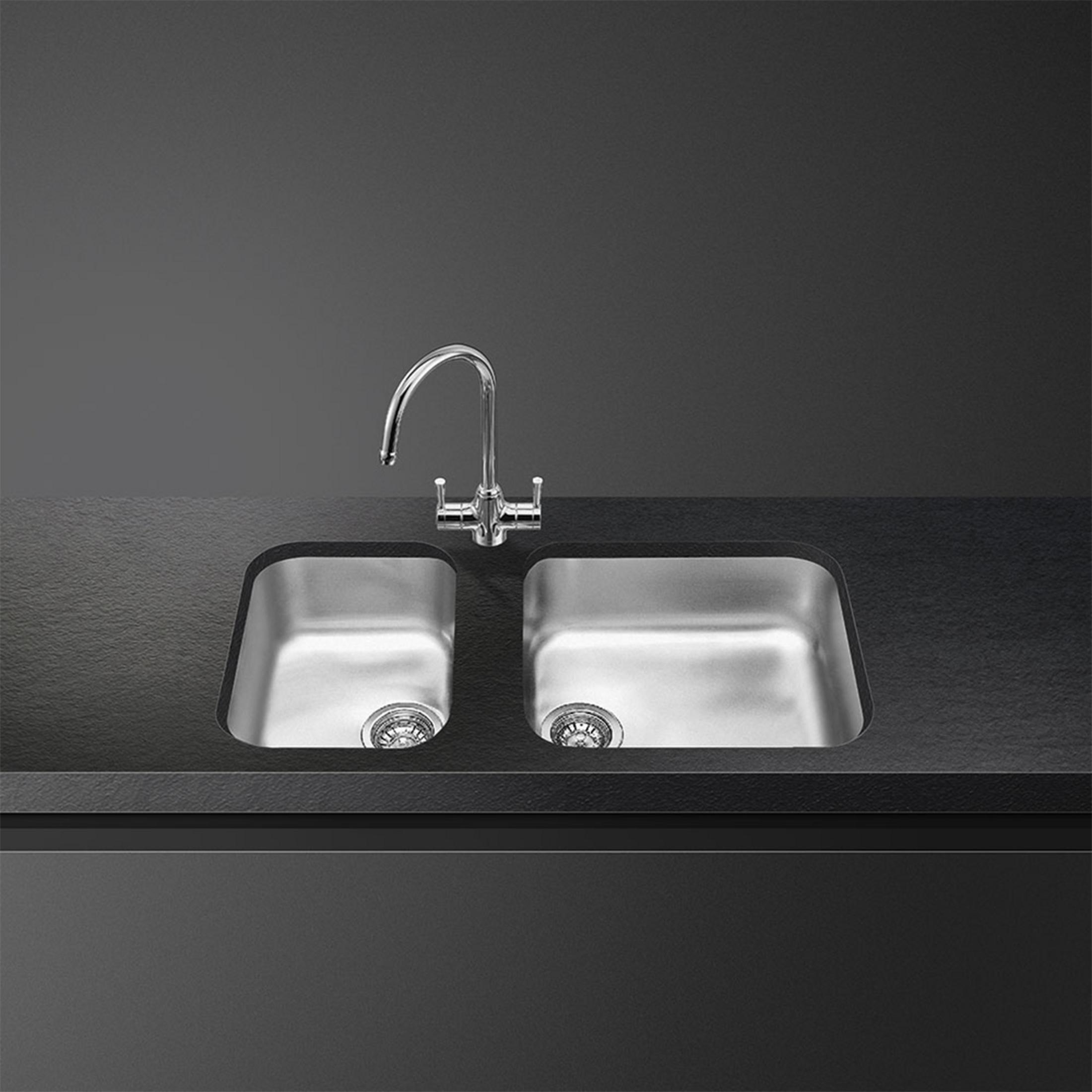 Fregadero doble de acero inoxidable con grifo brillante sobre encimera oscura.