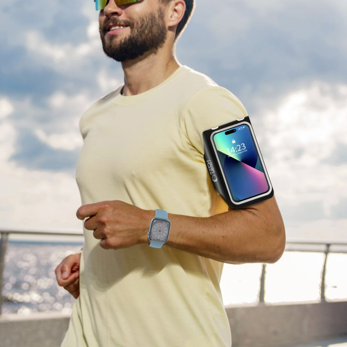Ein Mann mit Bart und Sonnenbrille läuft mit einem Handy-Armband und einer Uhr.
