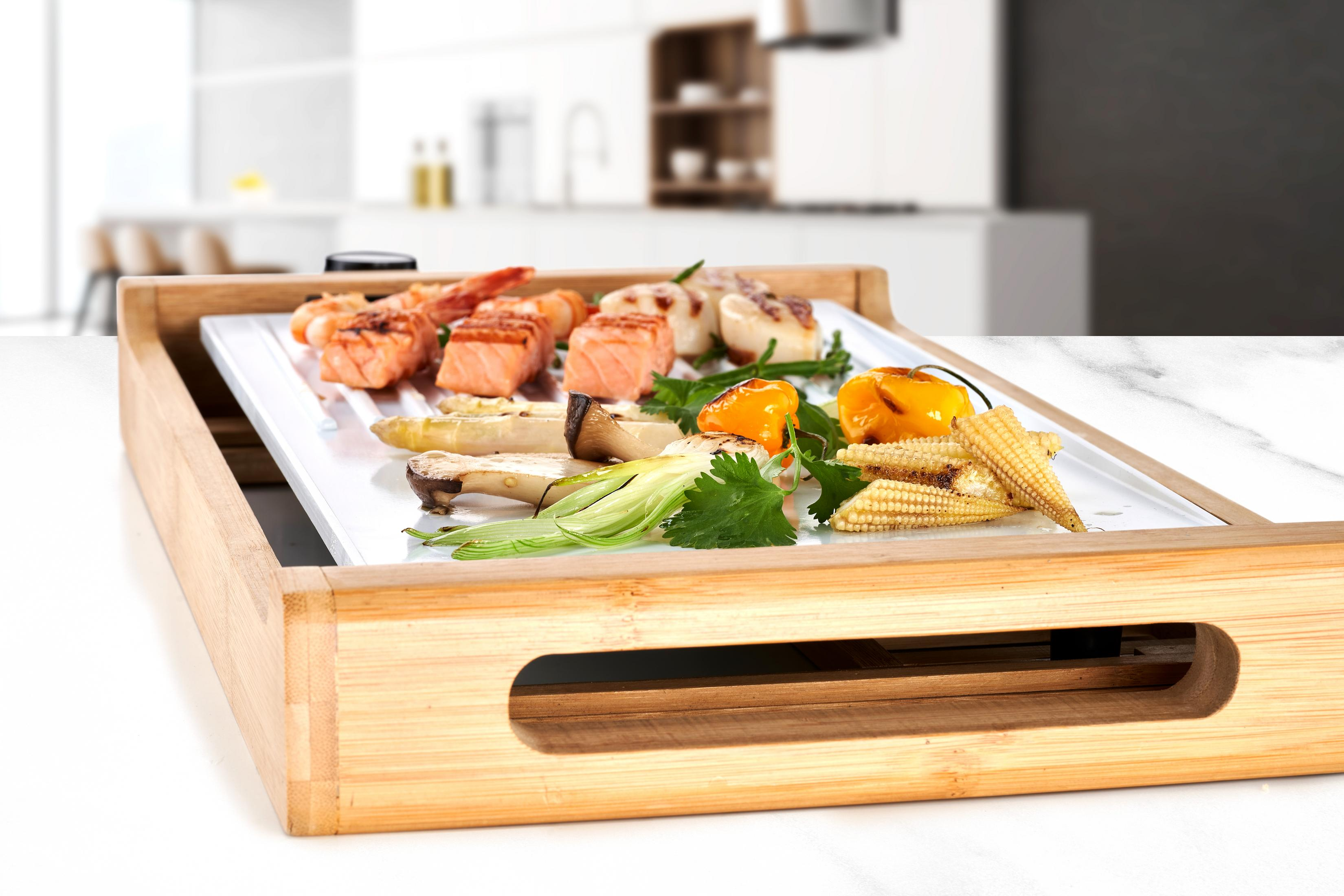 Salmone, gamberi, capesante, mais e verdure grigliate su piatto in legno.