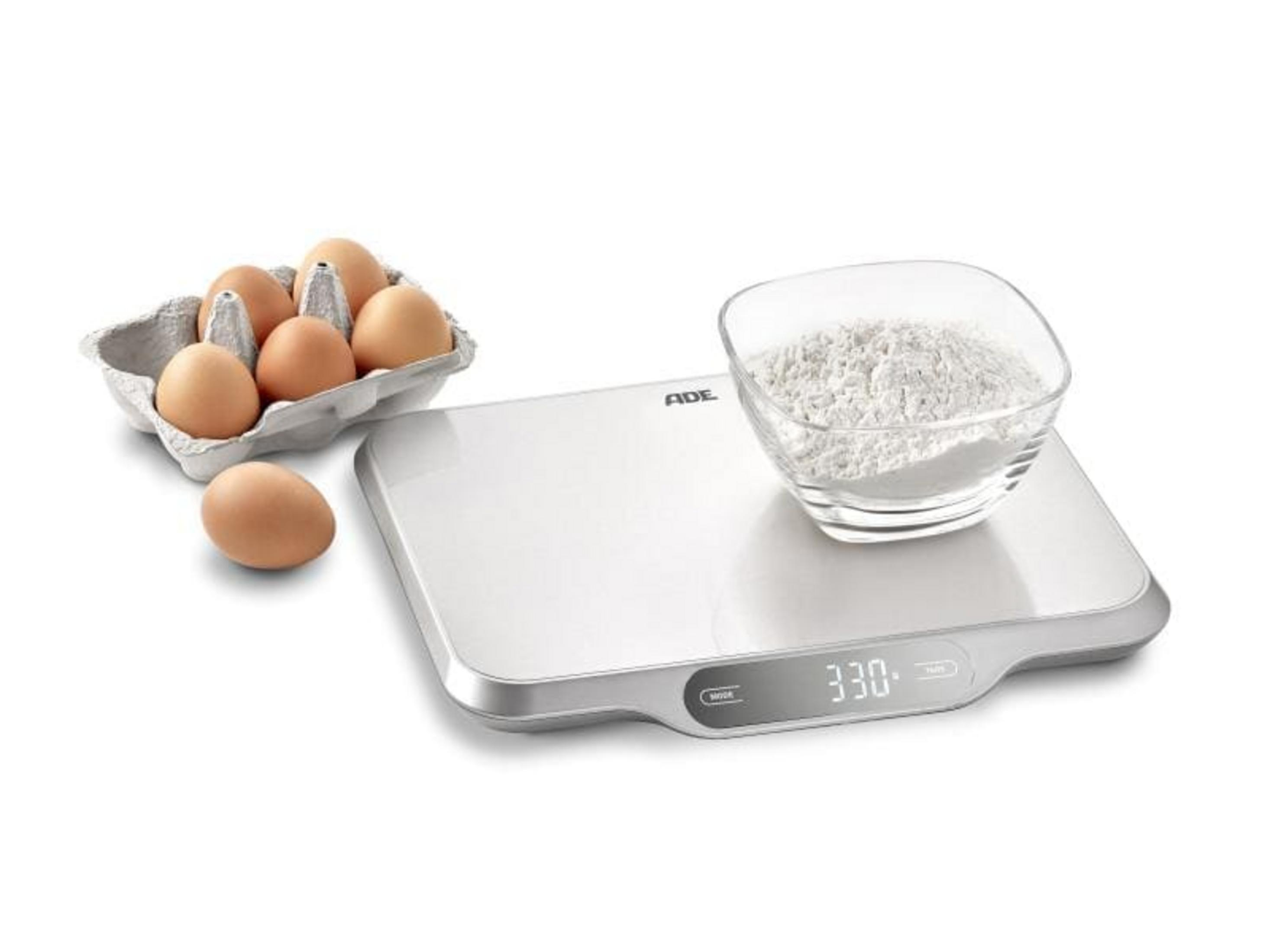 Una bilancia da cucina digitale con uova e farina in una ciotola.