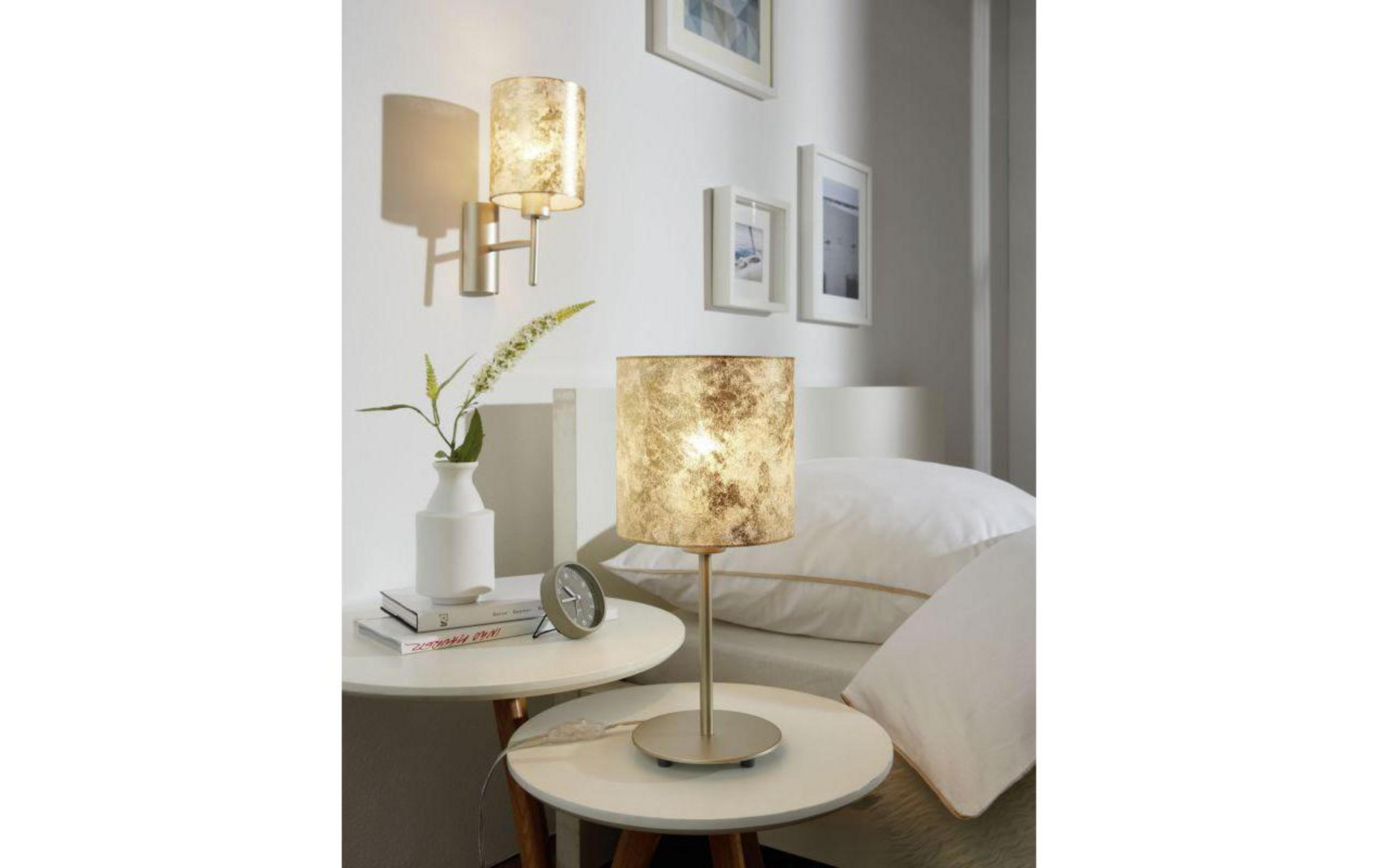 Ein Nachttisch mit Lampe, Buch, Vase und Uhr neben einem Bett.