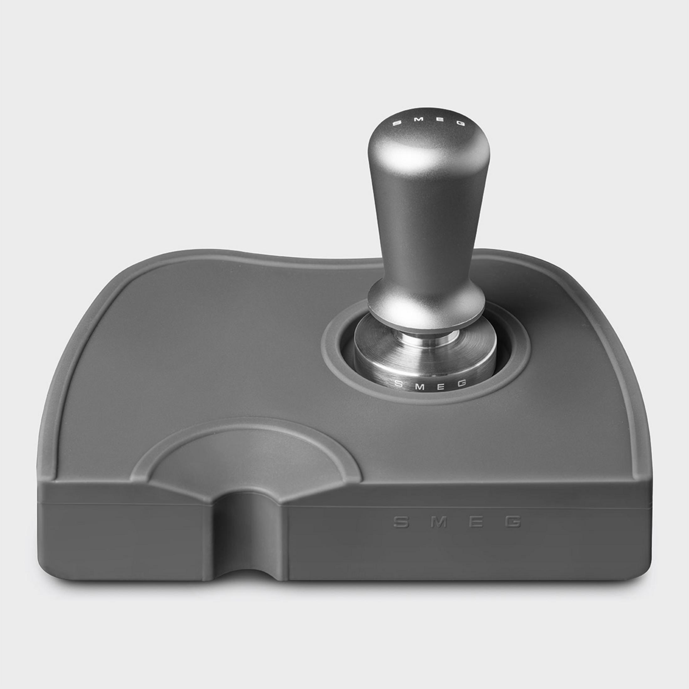 Pressino grigio con manico argentato su tappetino grigio con logo SMEG.