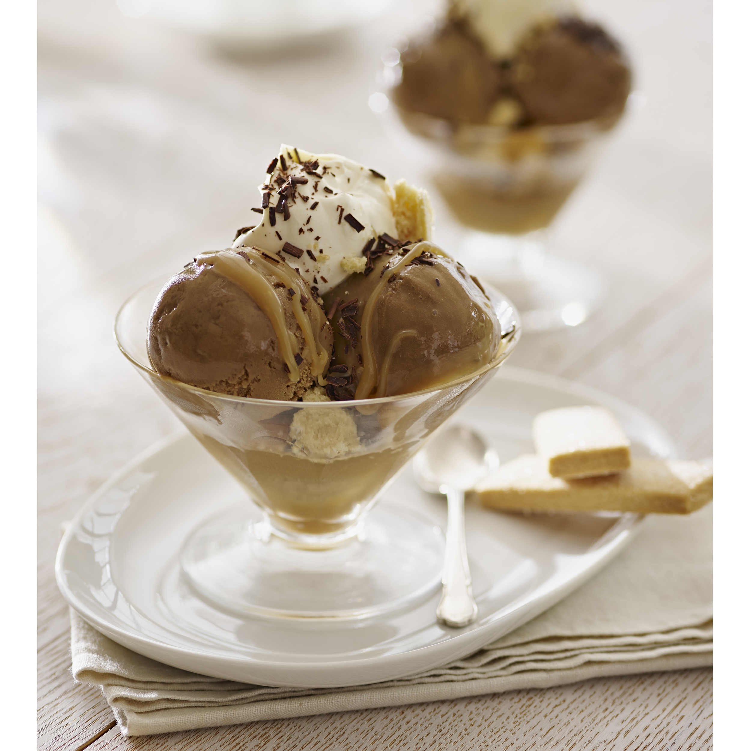 Gelato al cioccolato in un bicchiere con panna, salsa e biscotti.