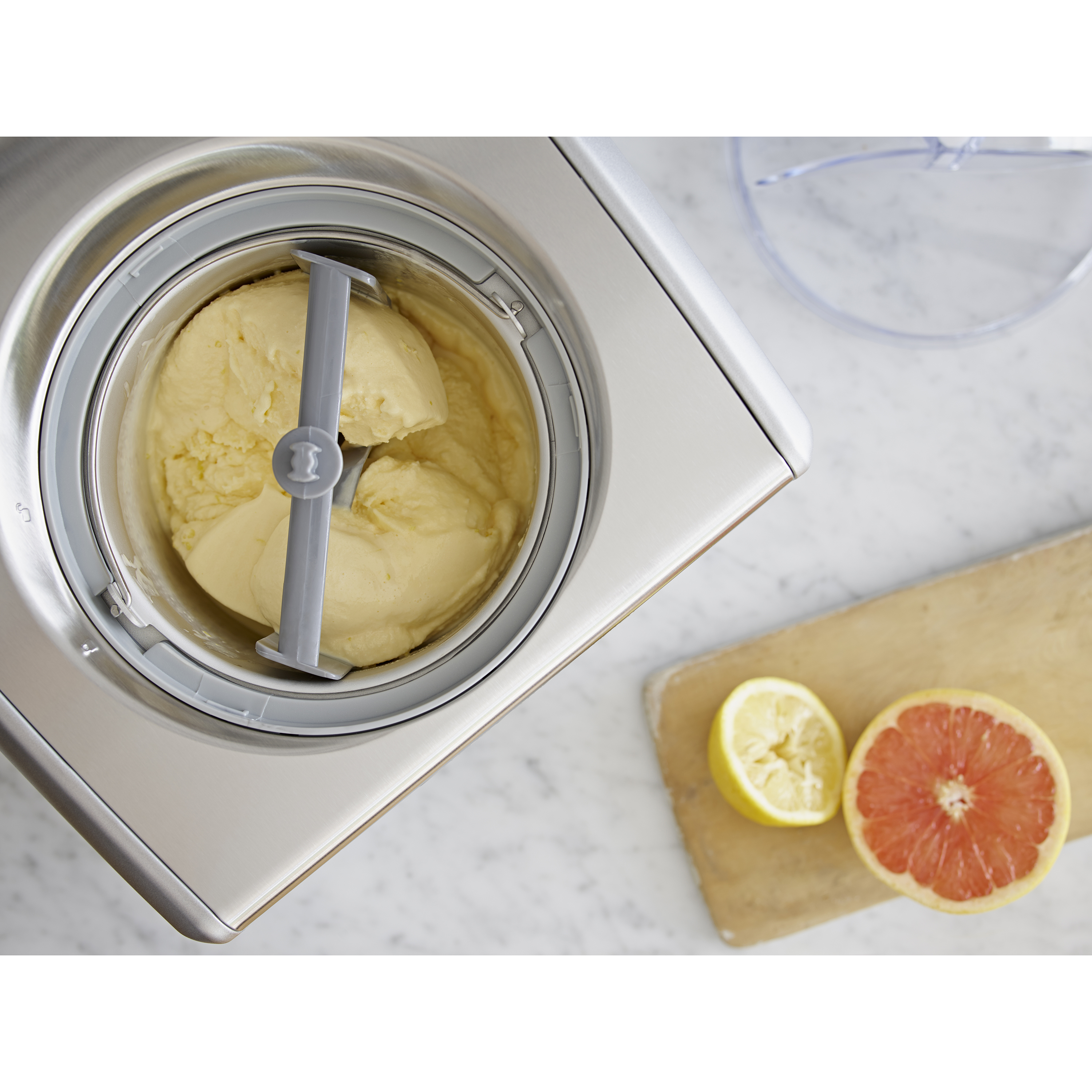 Una gelatiera con gelato, limone e pompelmo accanto.