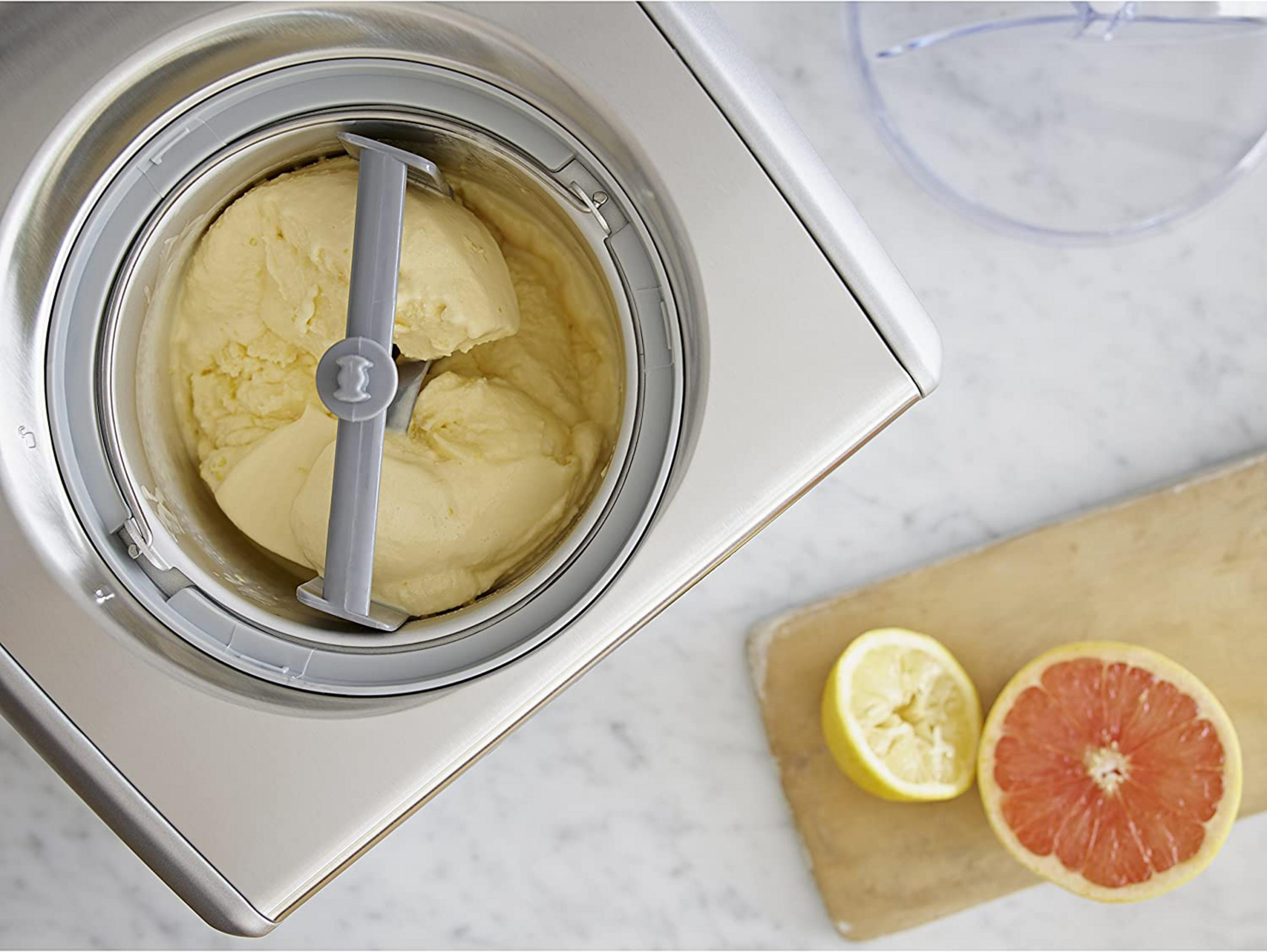 Gelatiera con gelato cremoso, limone e pompelmo sul tavolo.