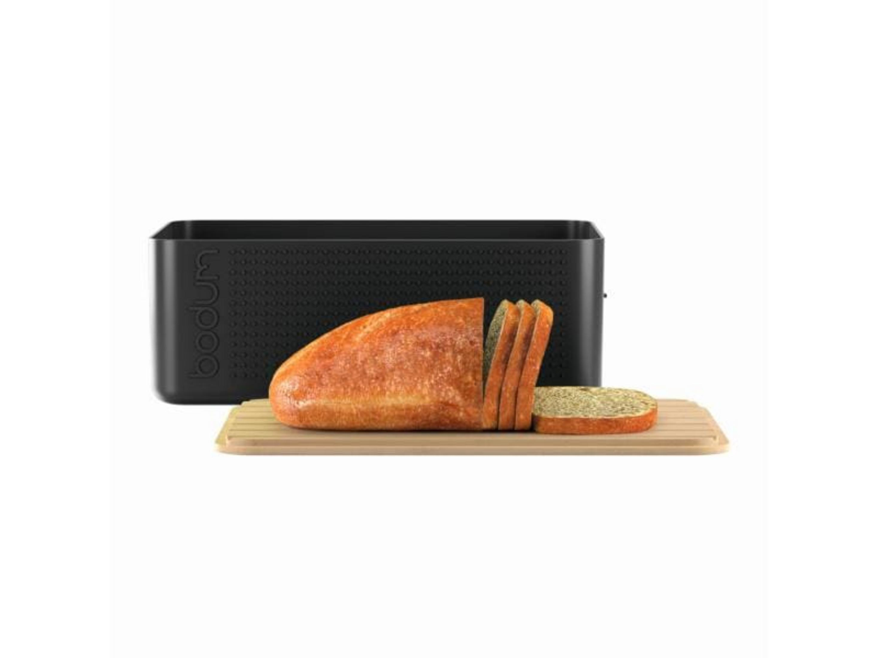 Ein Laib Brot, teilweise geschnitten, auf einem Holzbrett, daneben ein schwarzer Brotkasten.