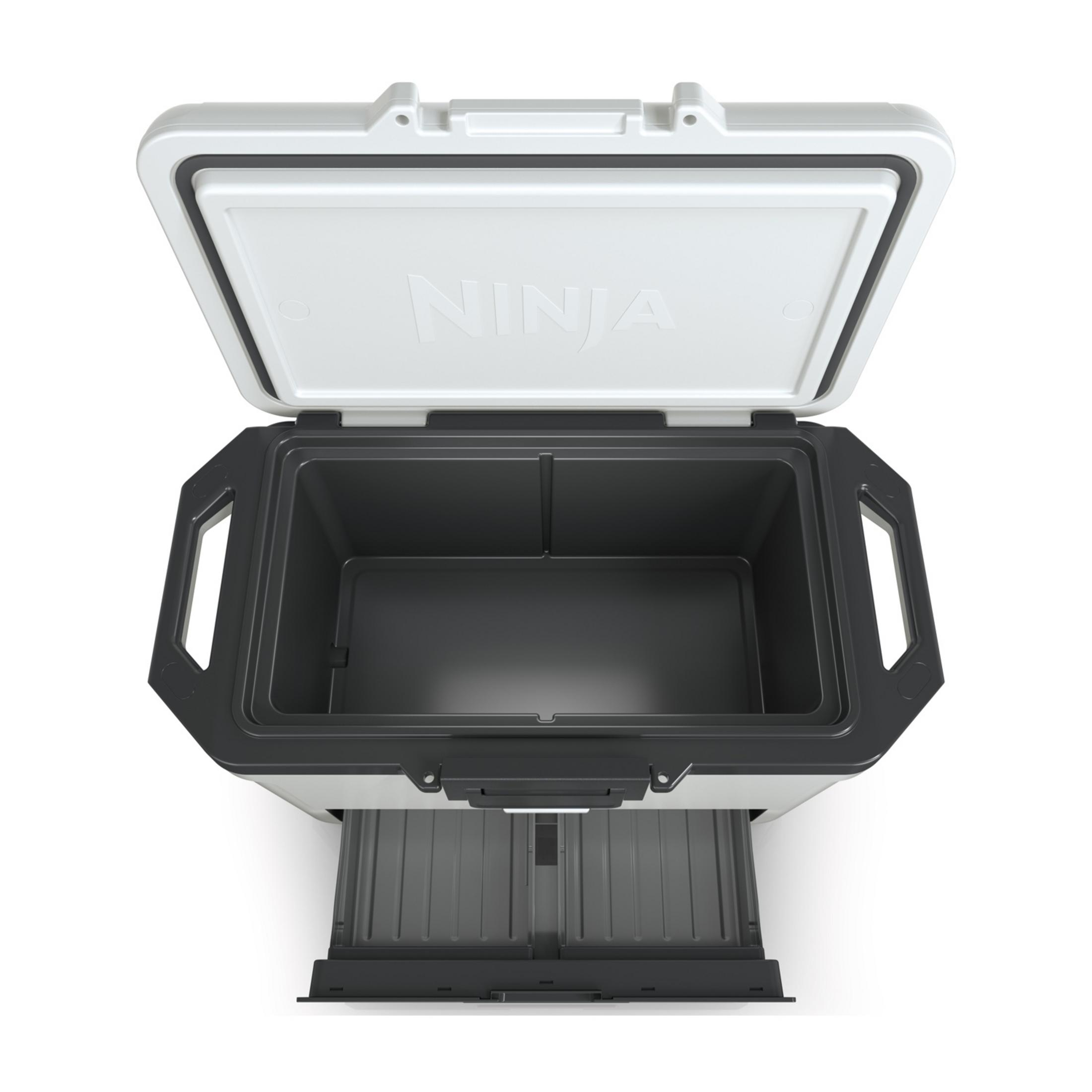 Biała i szara lodówka turystyczna Ninja z otwartą pokrywą i wysuwaną szufladą.