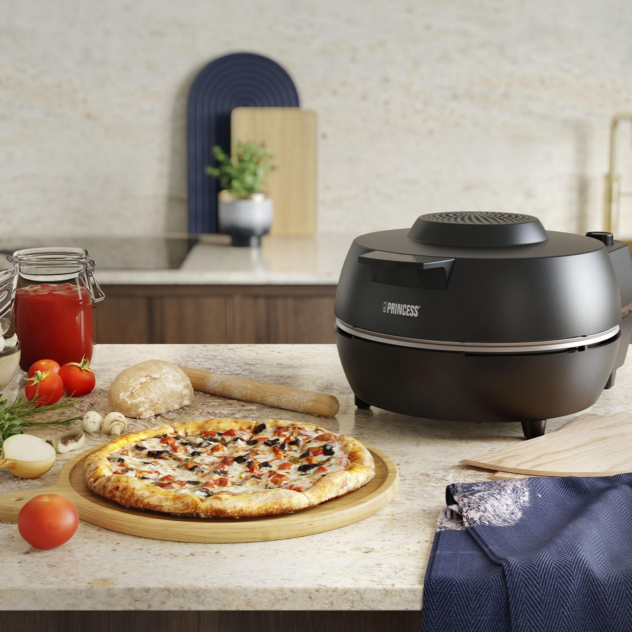 Una pizza cocinada e ingredientes en una encimera junto a un horno para pizza.