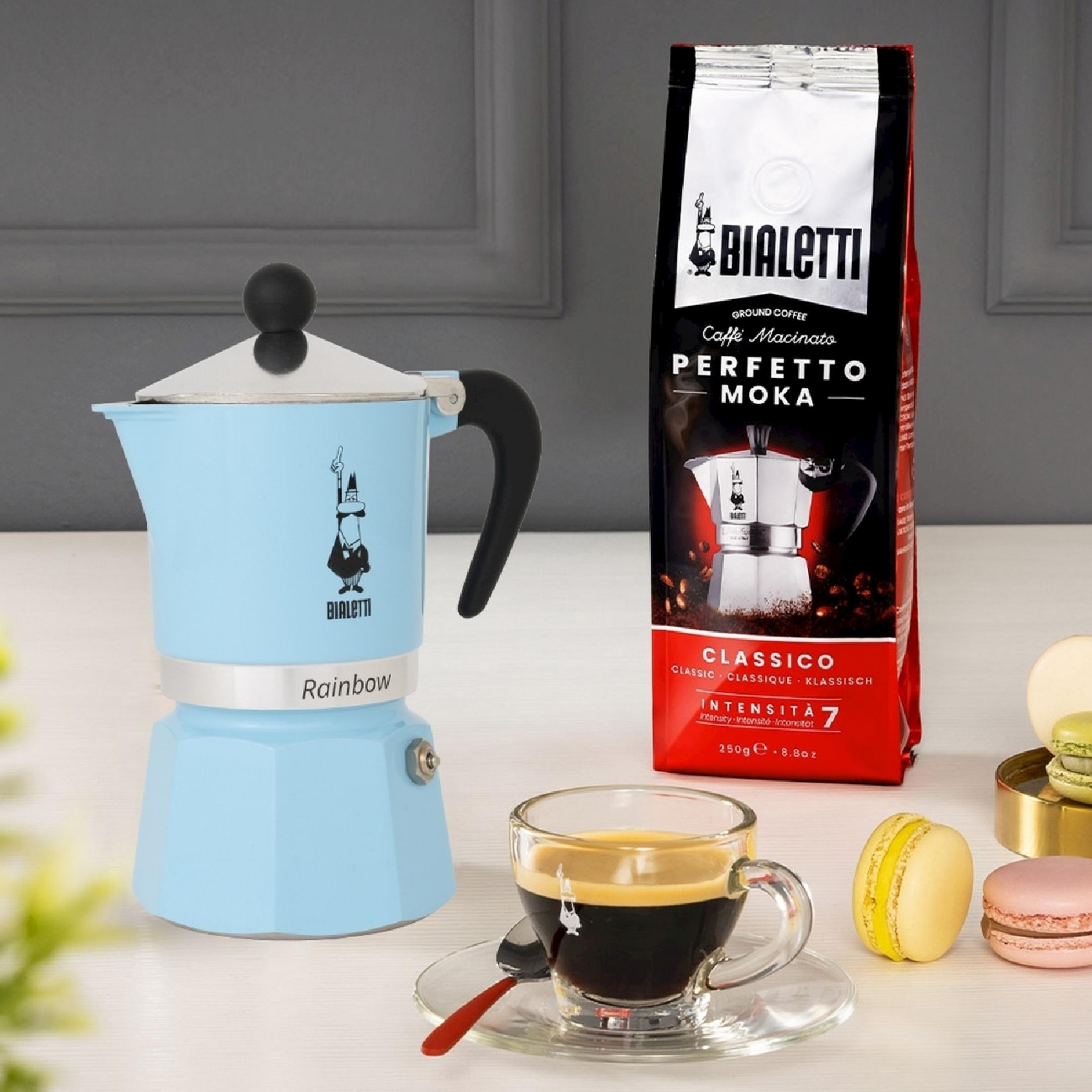 Hellblaue Mokkakanne neben einem Kaffeebeutel und einer Espressotasse mit Macarons.