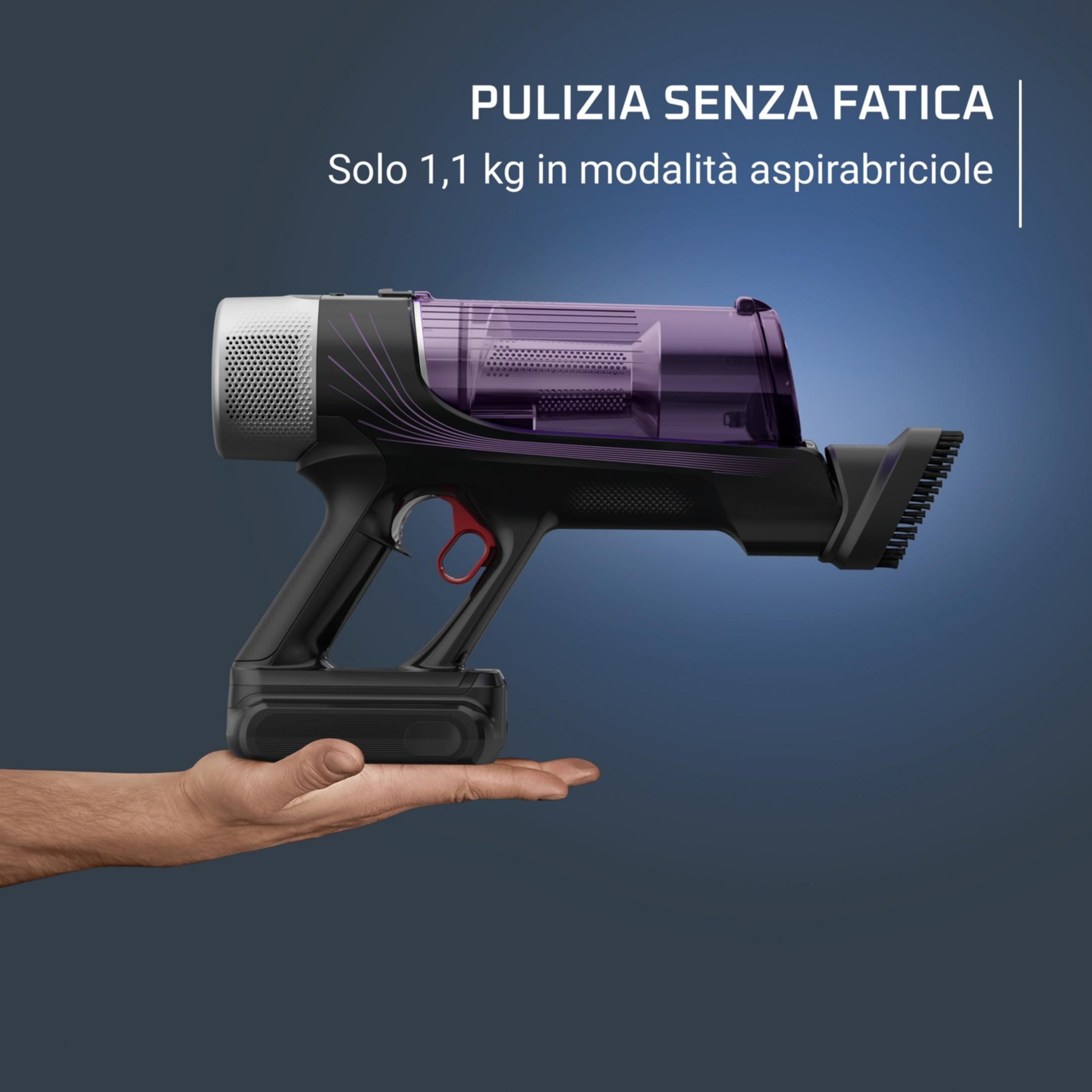 Un hombre sostiene una aspiradora de mano ligera y negra con depósito morado.
