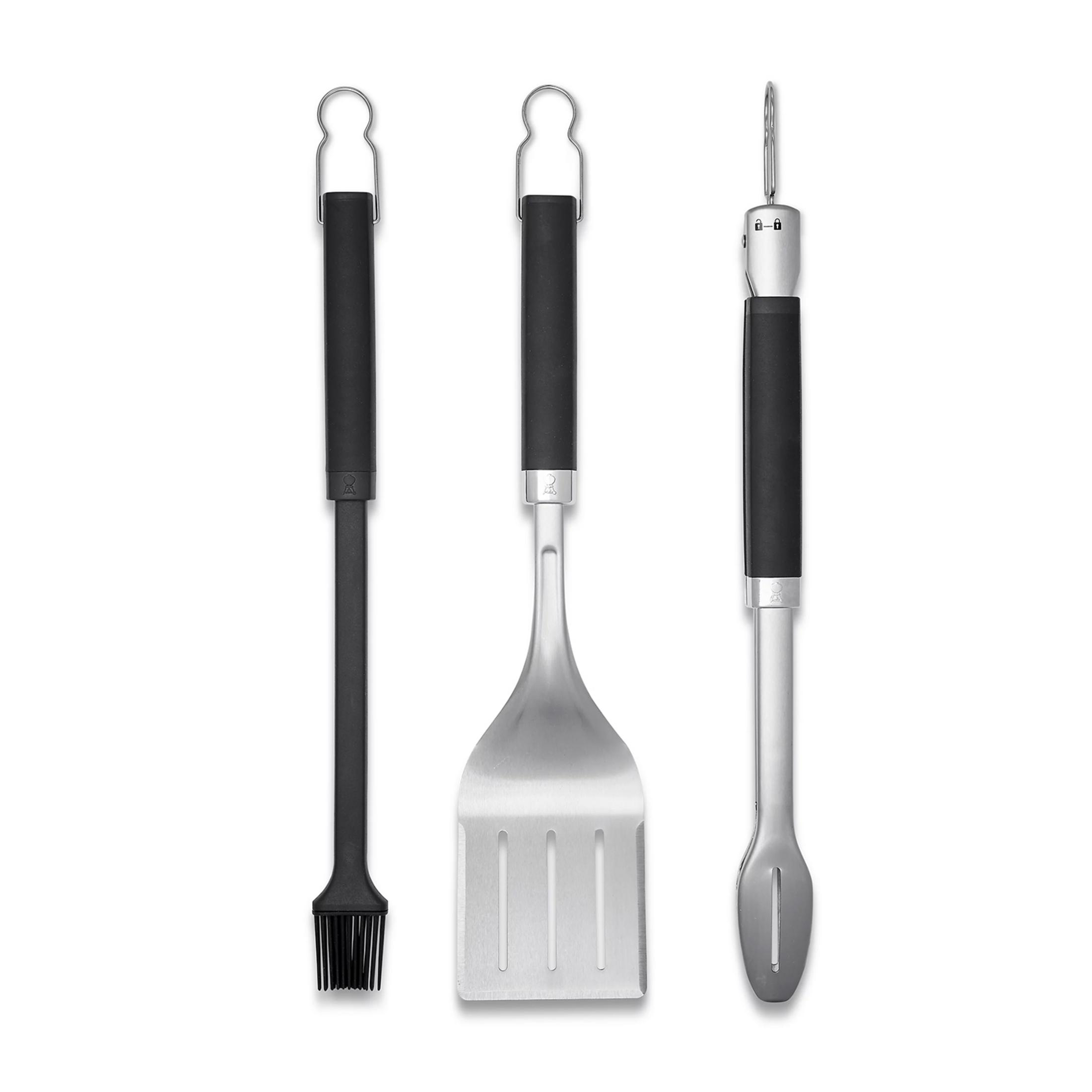 Ein Grillpinsel, ein Pfannenwender und eine Zange mit schwarzen Griffen.