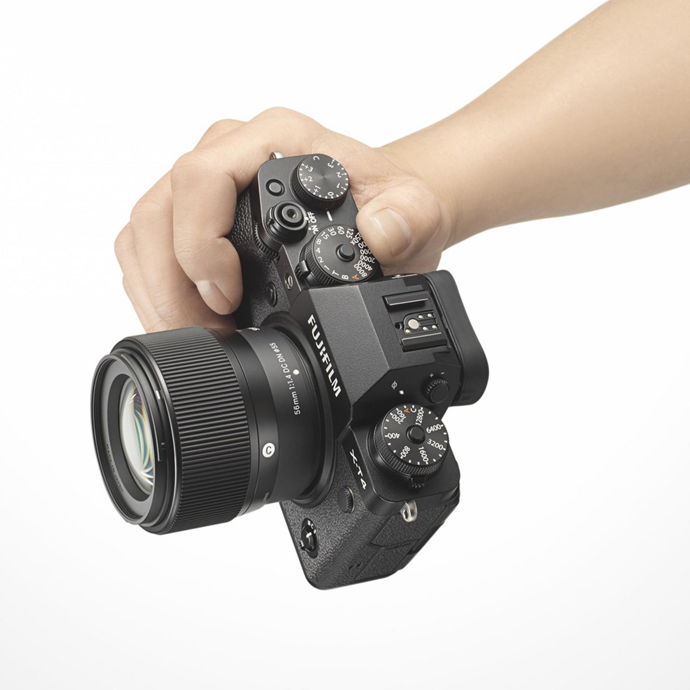 Dłoń trzyma czarny aparat Fujifilm X-T4 z obiektywem.