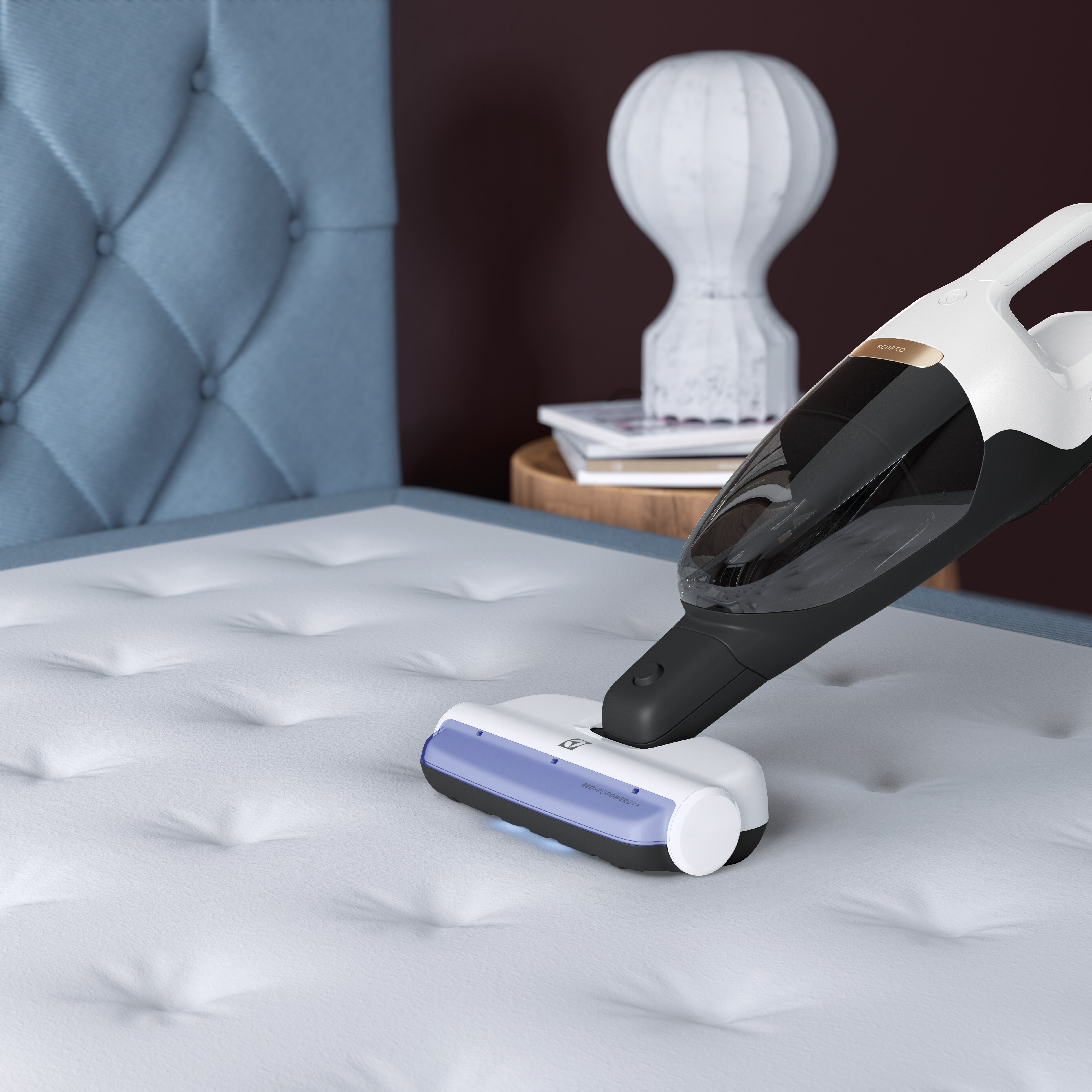 Un aspirateur à main nettoie un matelas blanc avec bordure bleue.