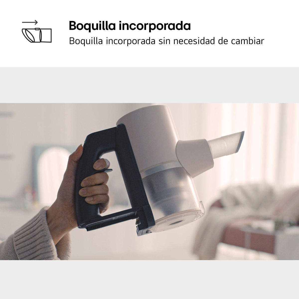 Una mano sostiene una aspiradora de mano blanca con mango negro. Boquilla integrada.