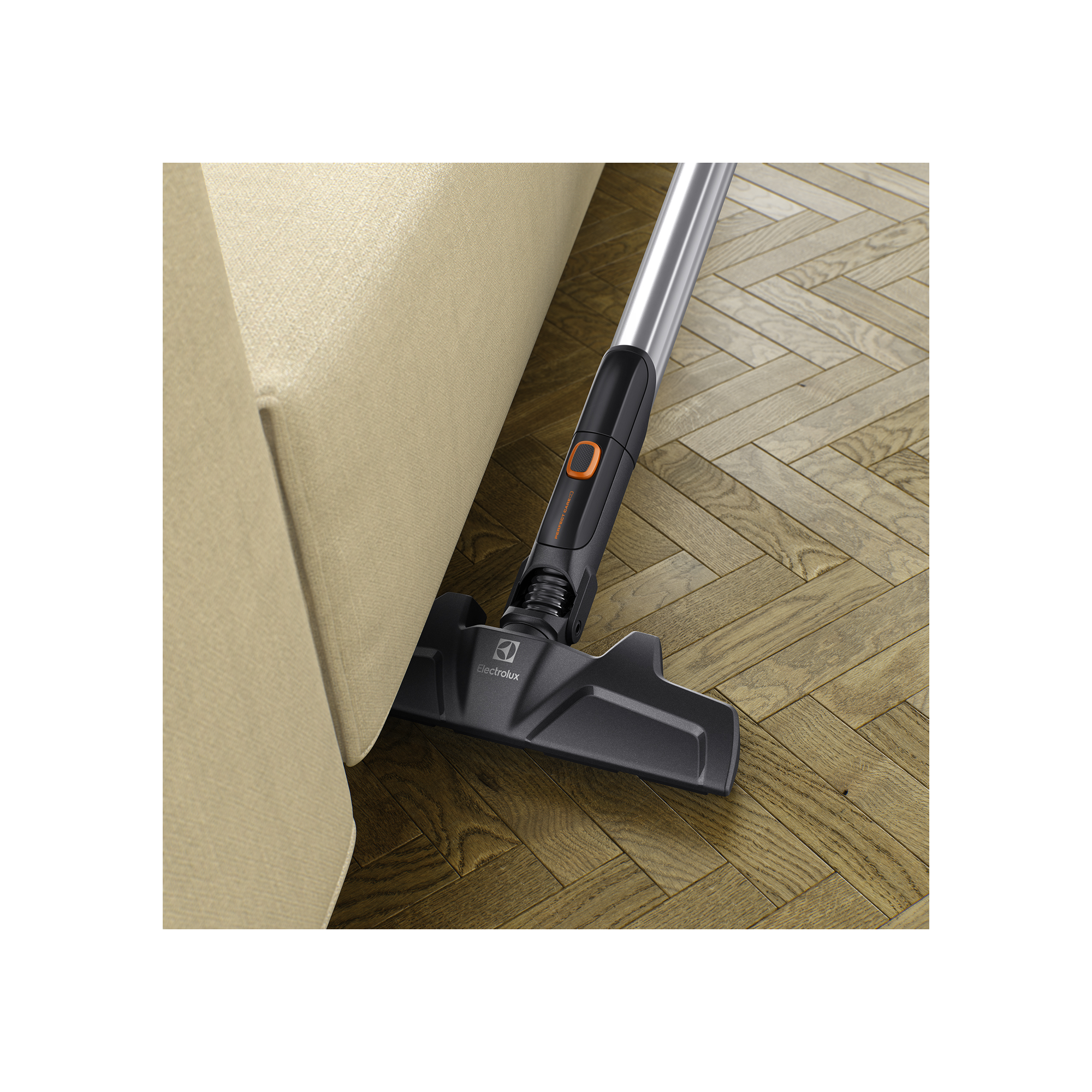Une tête d'aspirateur nettoie un plancher en bois à côté d'un canapé beige clair.