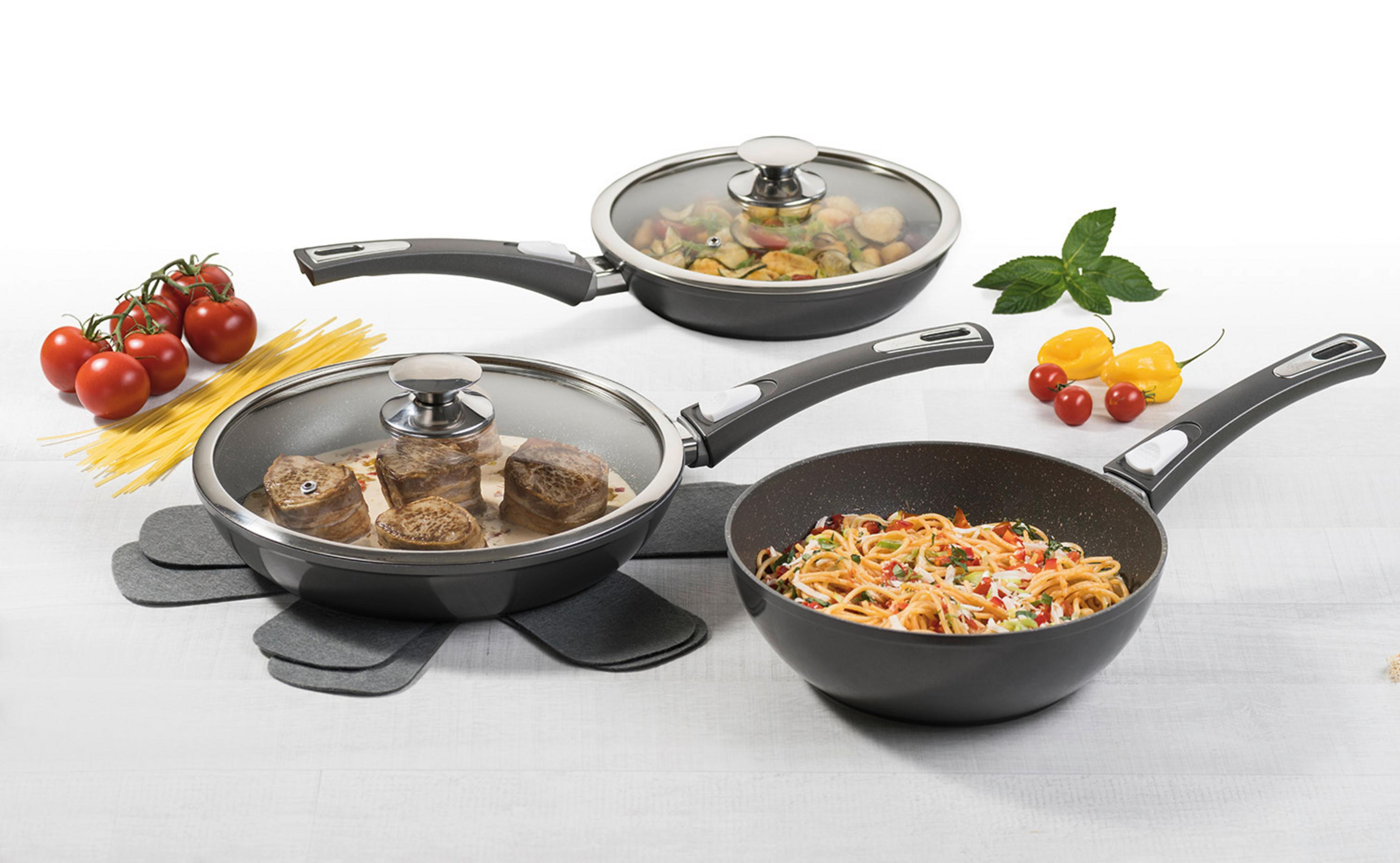 Trois poêles avec nourriture : viande, légumes et pâtes. Ingrédients à côté.