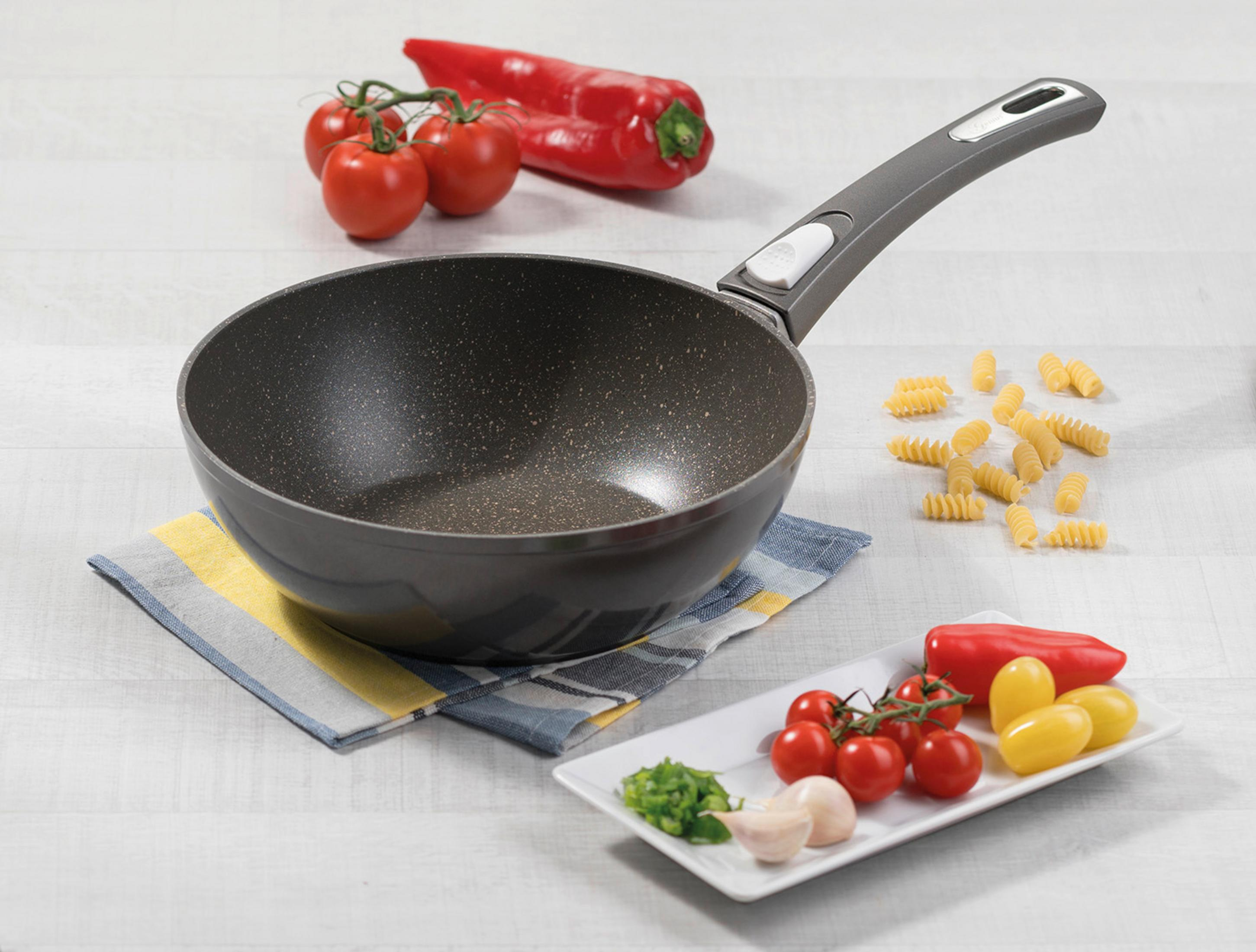 Une poêle avec des ingrédients tels que tomates, poivrons, ail et pâtes.
