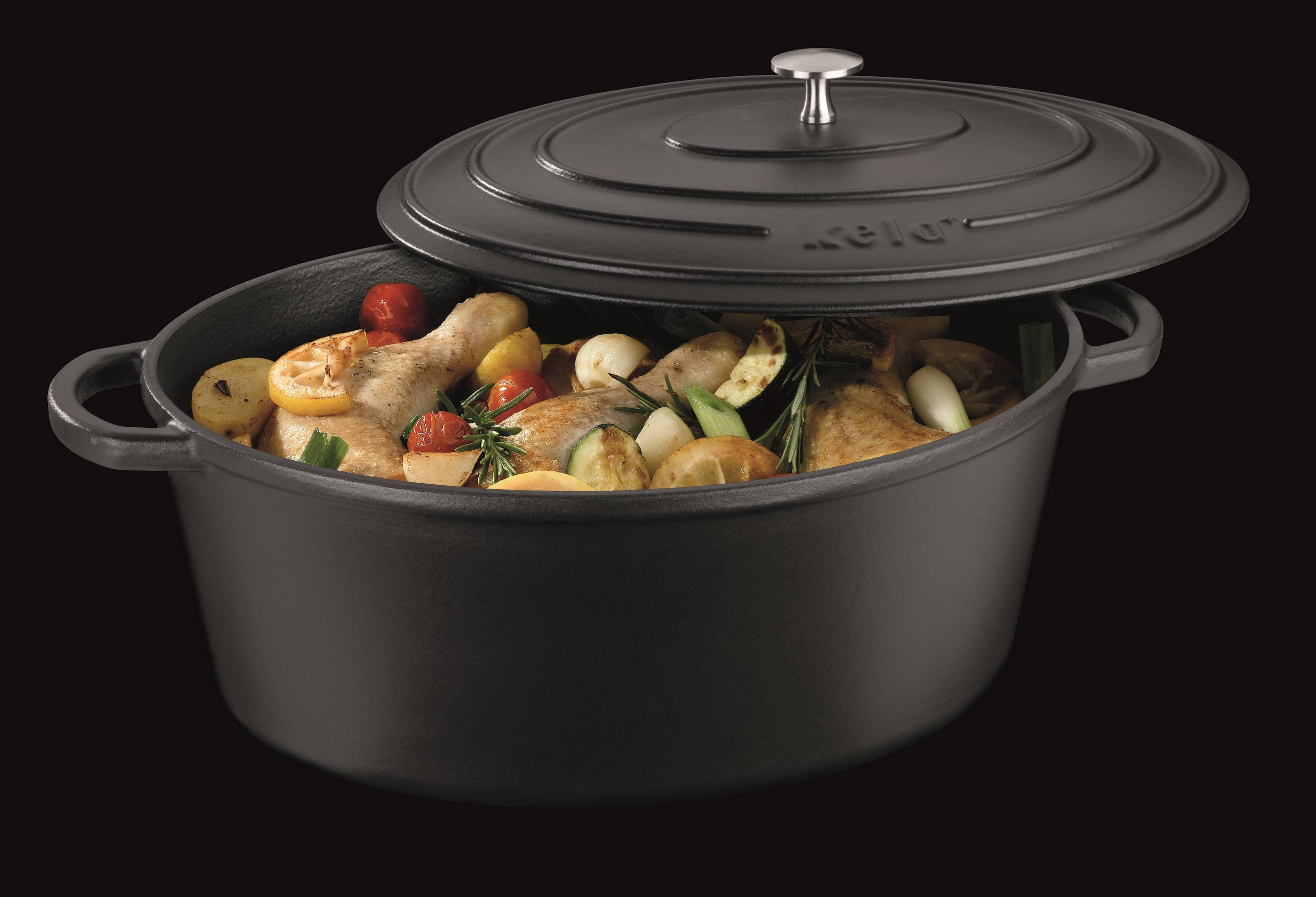 Une cocotte noire remplie de poulet, pommes de terre, citron et tomates.