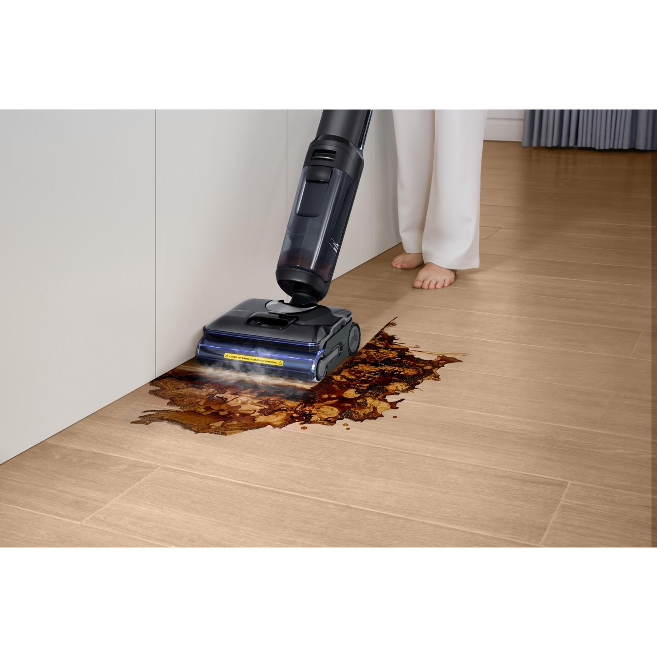 Odkurzacz na mokro/sucho czyści brązowy płyn na drewnianej podłodze.