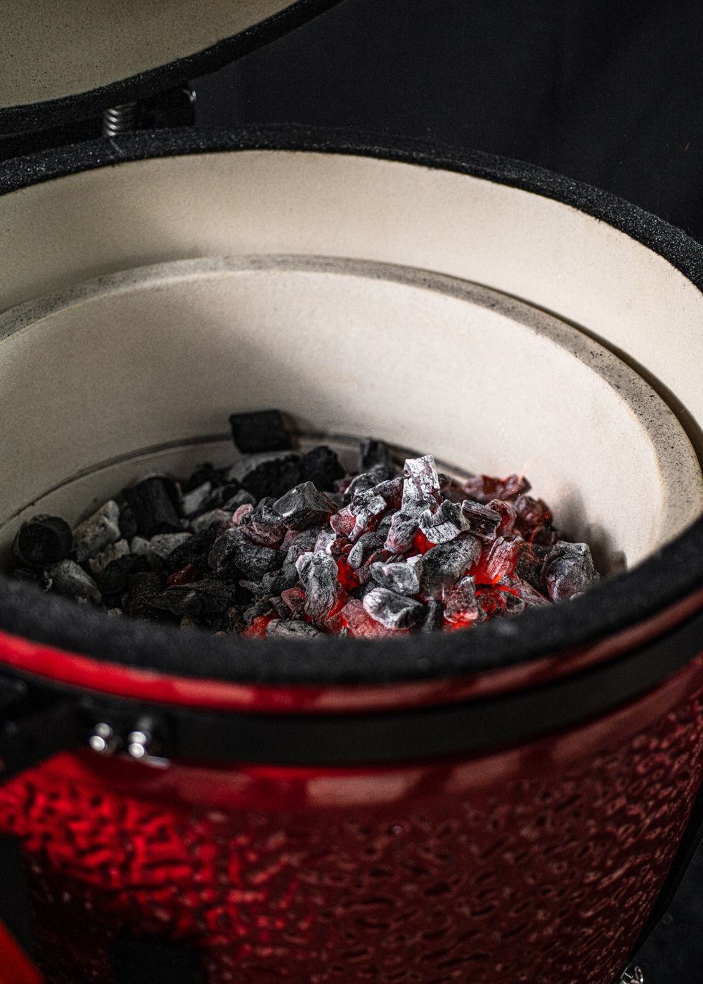 Brasas incandescentes en una parrilla roja de cerámica con borde negro.