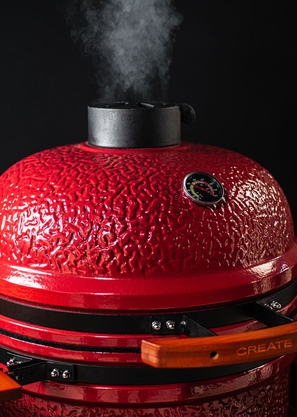 Parrilla roja de cerámica con humo y termómetro.