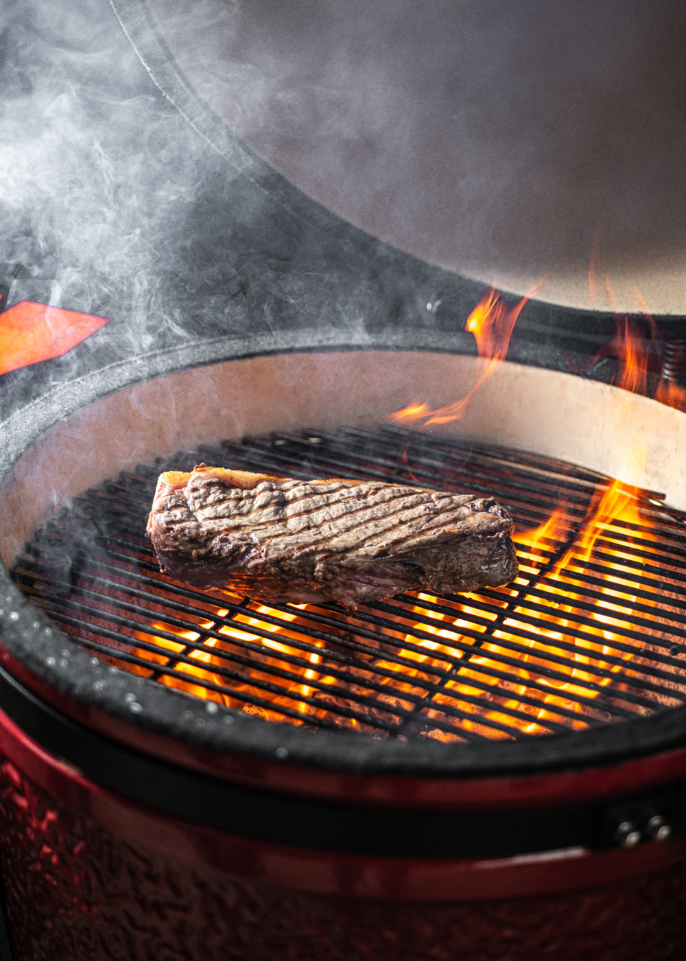 Un filete se cocina en una parrilla sobre llamas calientes y humo.
