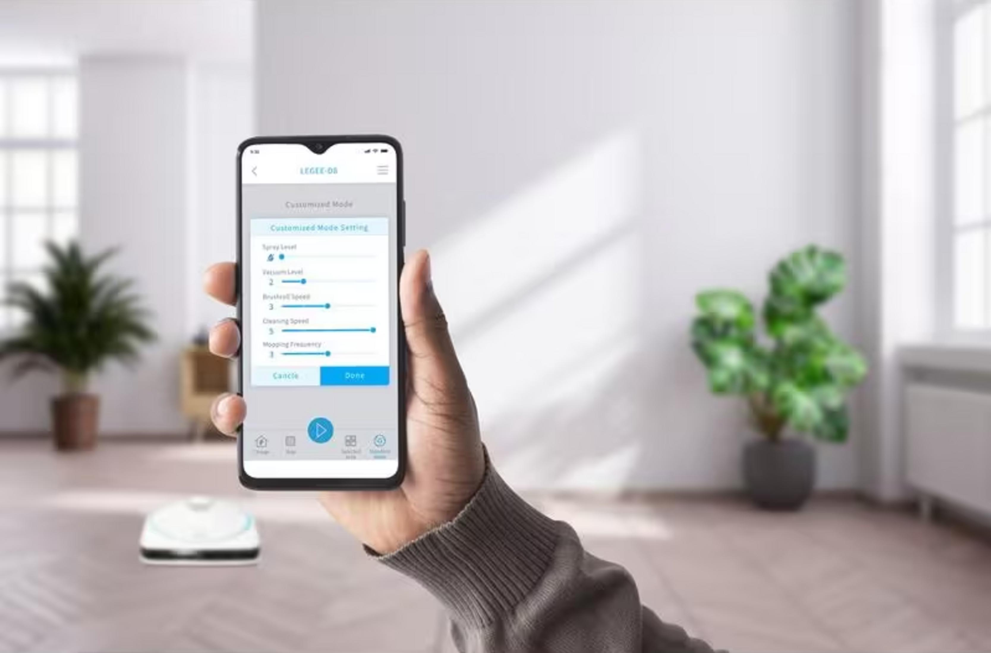 Eine Hand hält ein Smartphone, das eine App zur Einstellung eines Saugroboters zeigt.