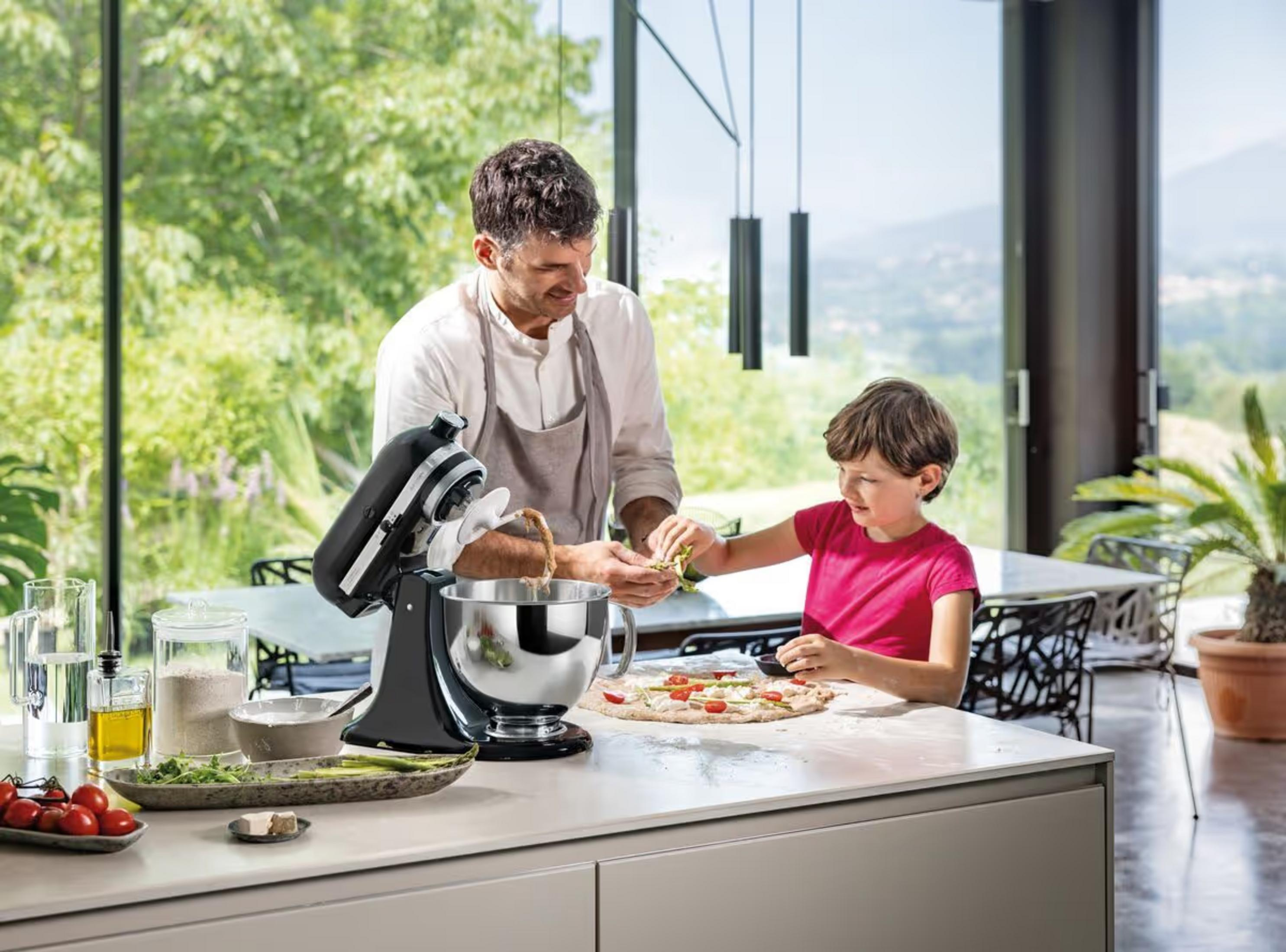 Uomo e bambino fanno pizza in cucina moderna con grande finestra.