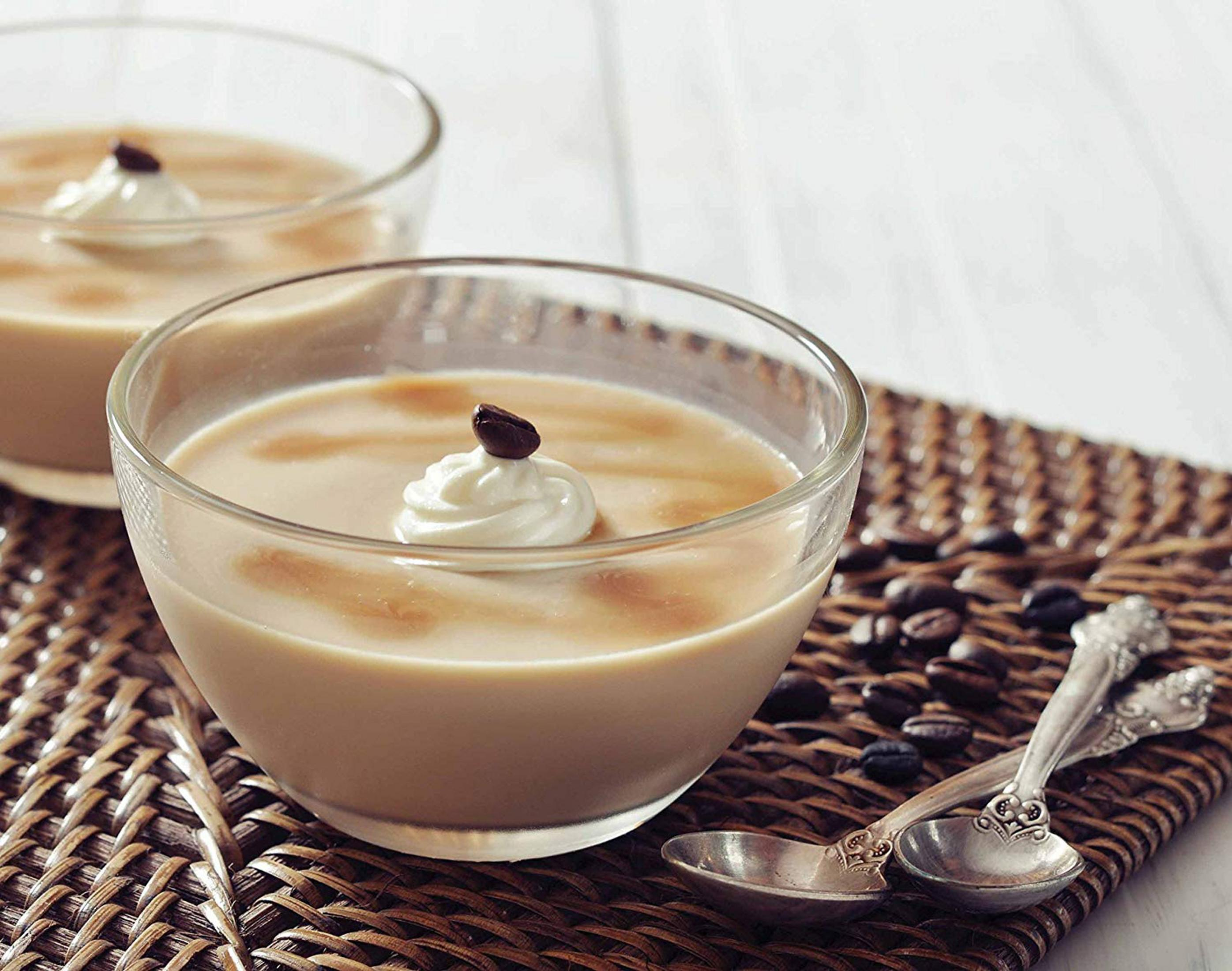 Due bicchieri di dessert alla crema di caffè, guarniti con panna montata e chicchi di caffè.