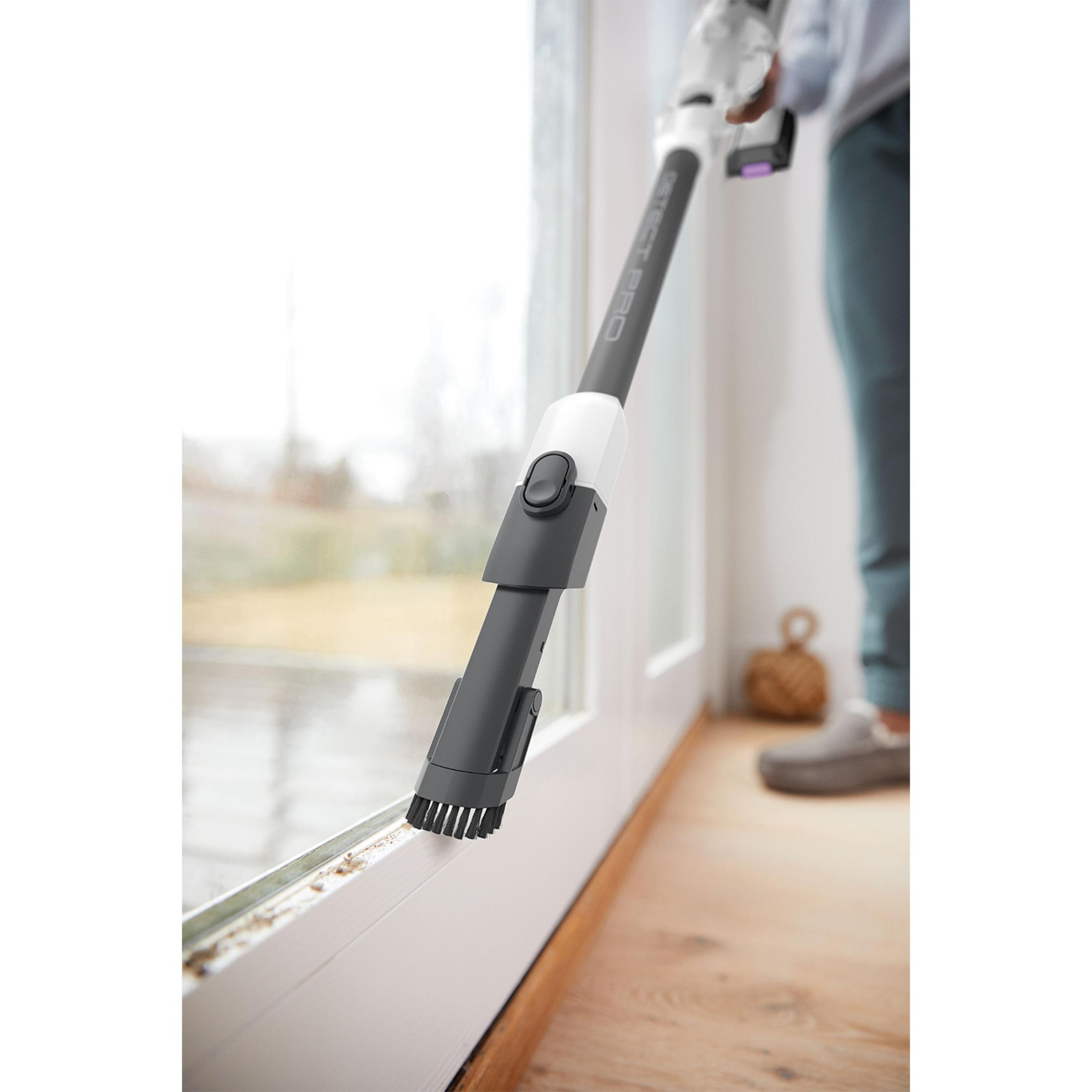 A vacuum cleaner is cleaning a dirty window sill next to a door.