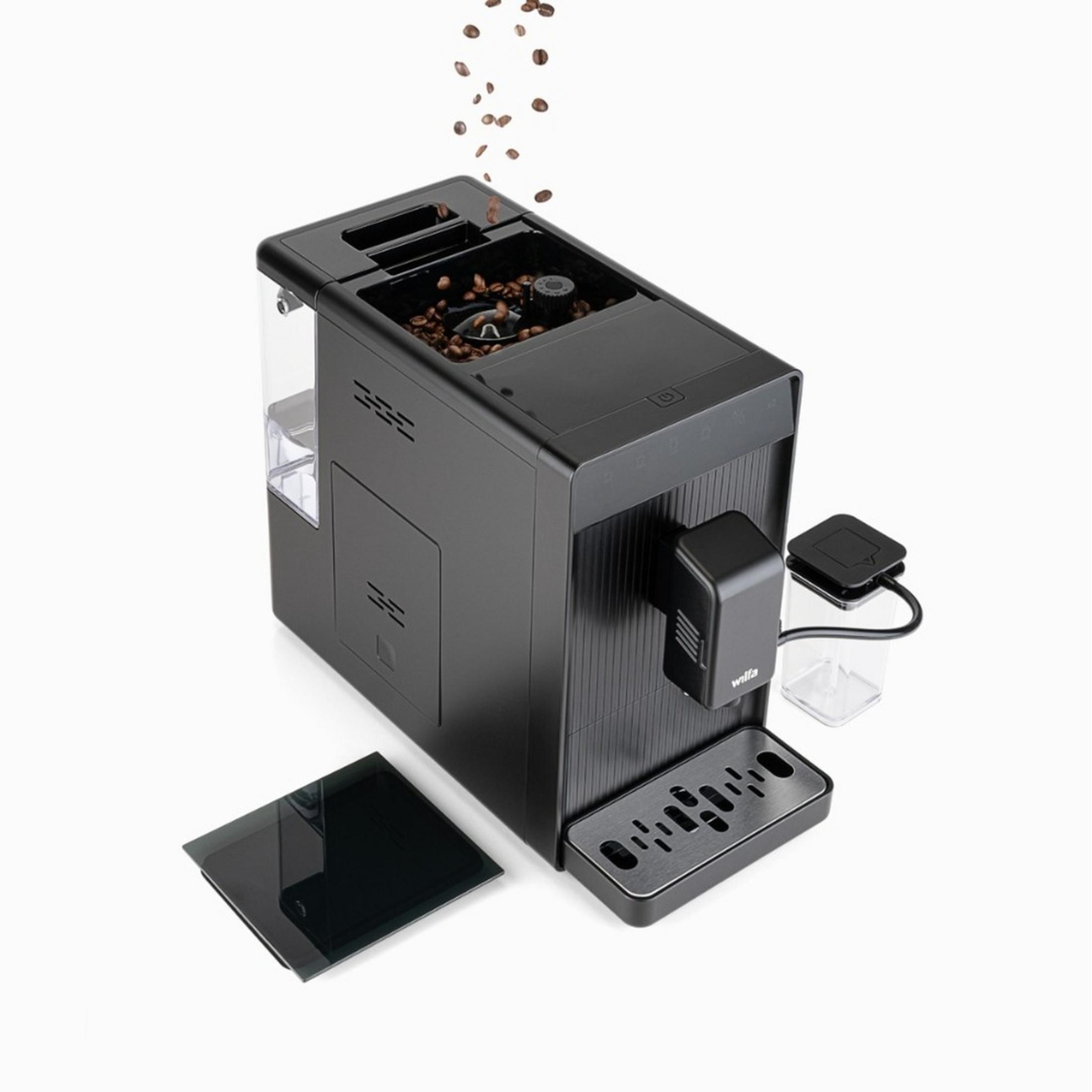 Cafetera negra con granos cayendo. Bandeja de goteo y depósito de agua visibles.