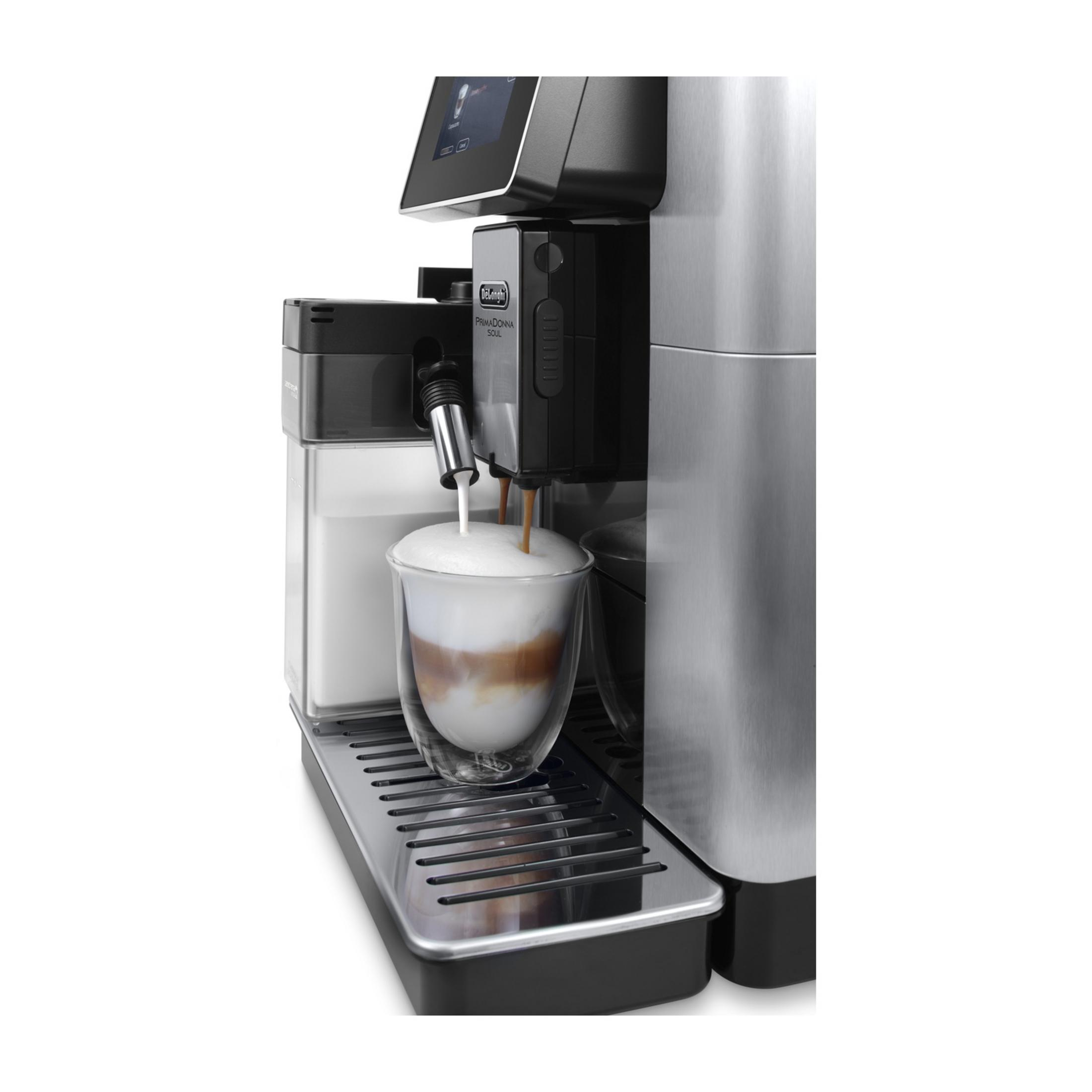 Coffee machine brewing latte into a double-walled glass. Milk and coffee mix.