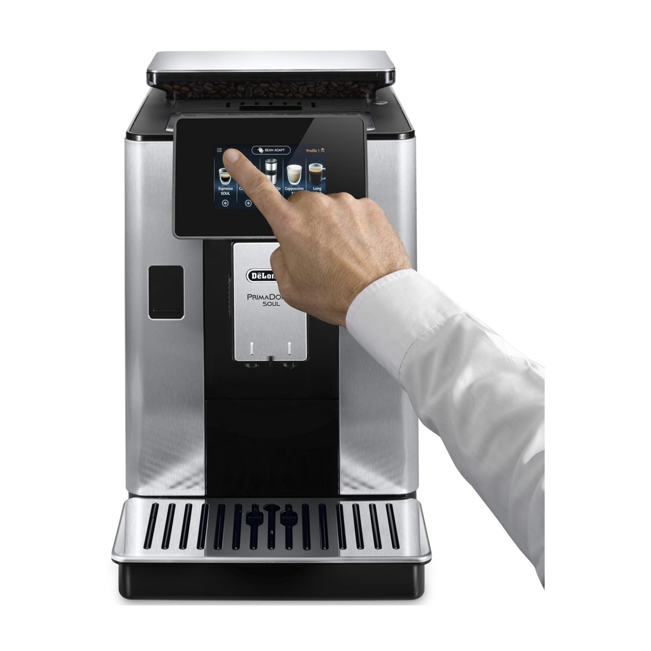 A hand touches the touchscreen of a coffee machine with coffee beans on top.